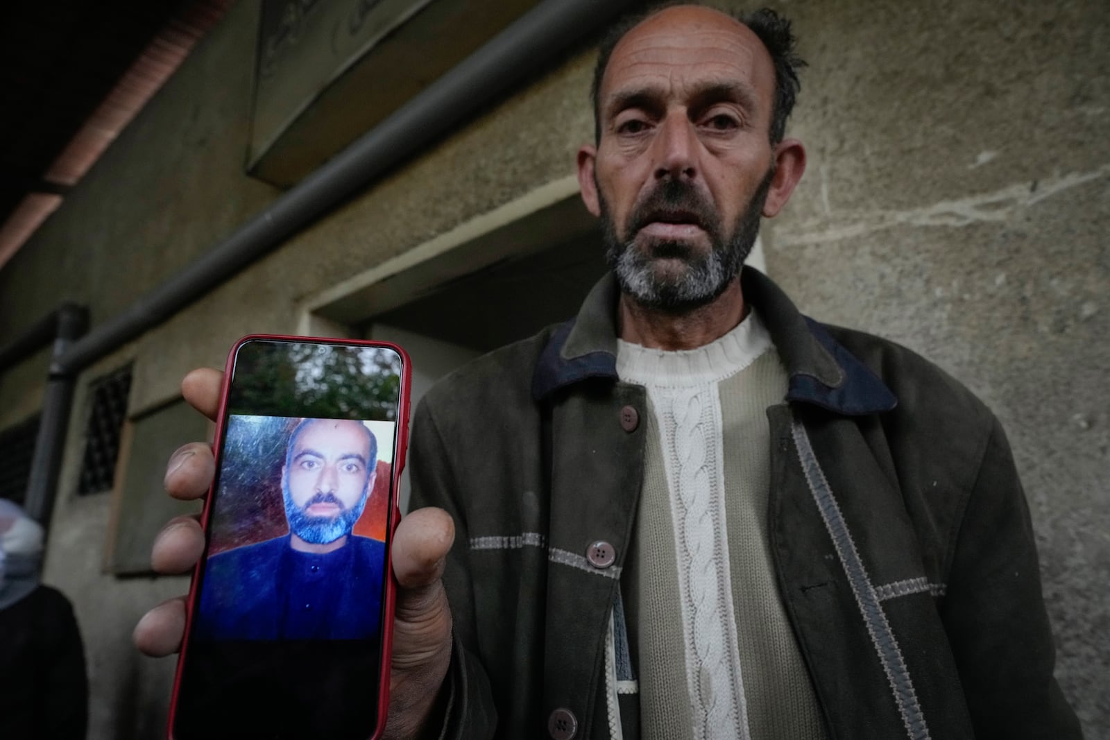 Abou Ahmad holds a picture of his son, who went missing while imprisoned by the late Syrian government, as he searches for his body at the Al-Mojtahed hospital morgue in Damascus, Syria, on Wednesday, Dec. 11, 2024. Many are flocking to morgues, hoping to identify loved ones who have been killed or were imprisoned under the rule of President Bashar Assad, whose government collapsed over the weekend.(AP Photo/Hussein Malla)