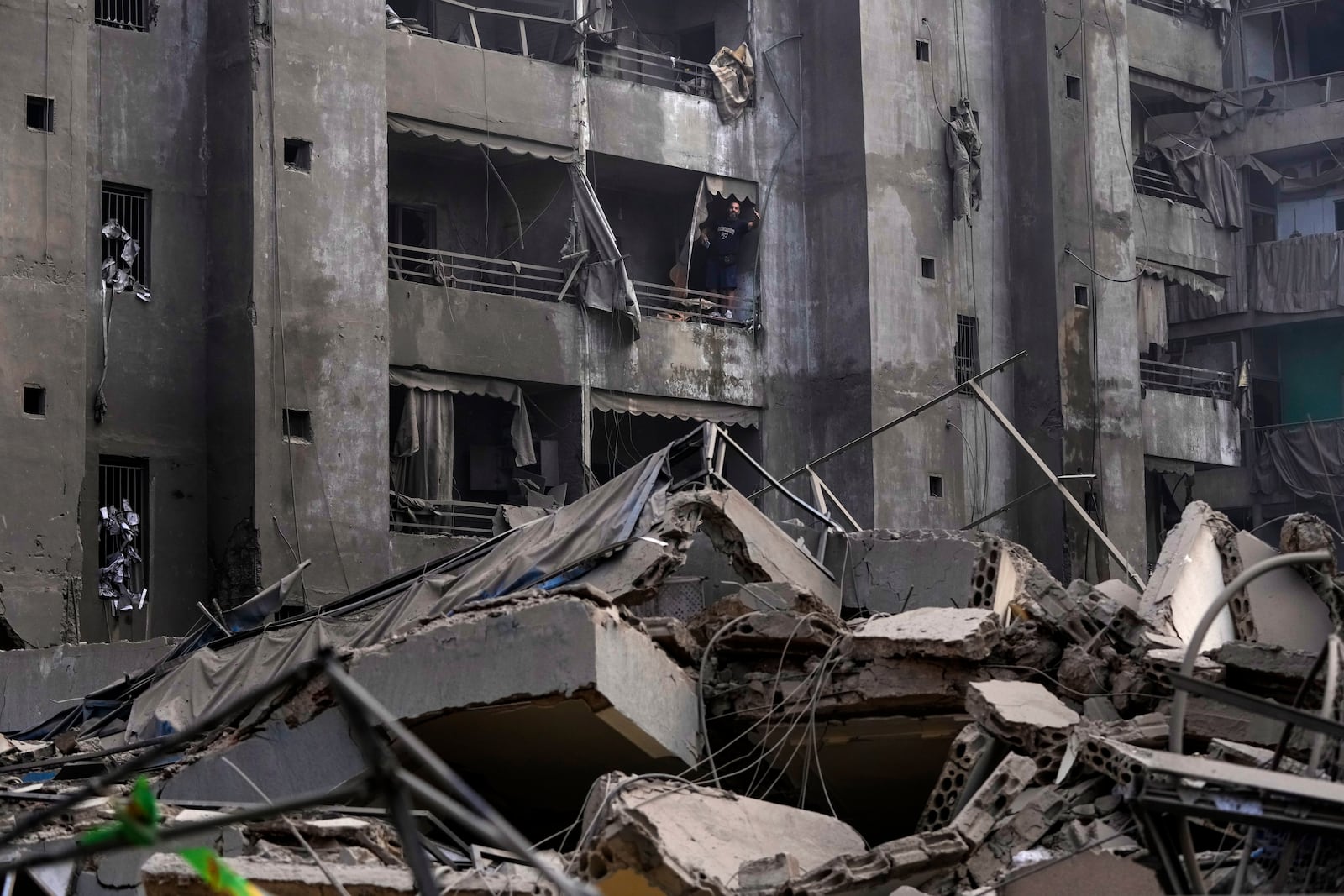 A man shouts slogans against Israel as he stands on the balcony of his damaged apartment at the site of an Israeli airstrike in Dahiyeh, Beirut, Lebanon, Friday, Nov. 1, 2024. (AP Photo/Hassan Ammar)