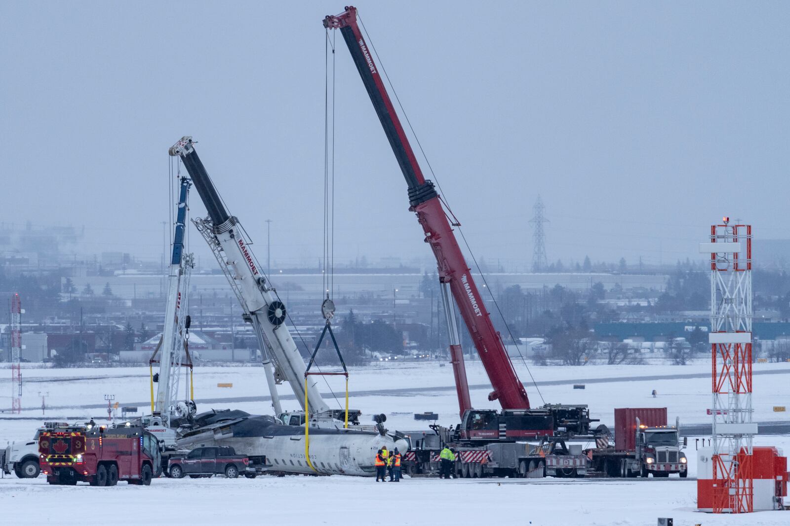 Cranes are positioned to remove the wreckage of Delta Flight 4819 from the runway at Toronto Pearson International Airport, in Mississauga, Ontario, on Wednesday, Feb. 19, 2025. (Arlyn McAdorey/The Canadian Press via AP)