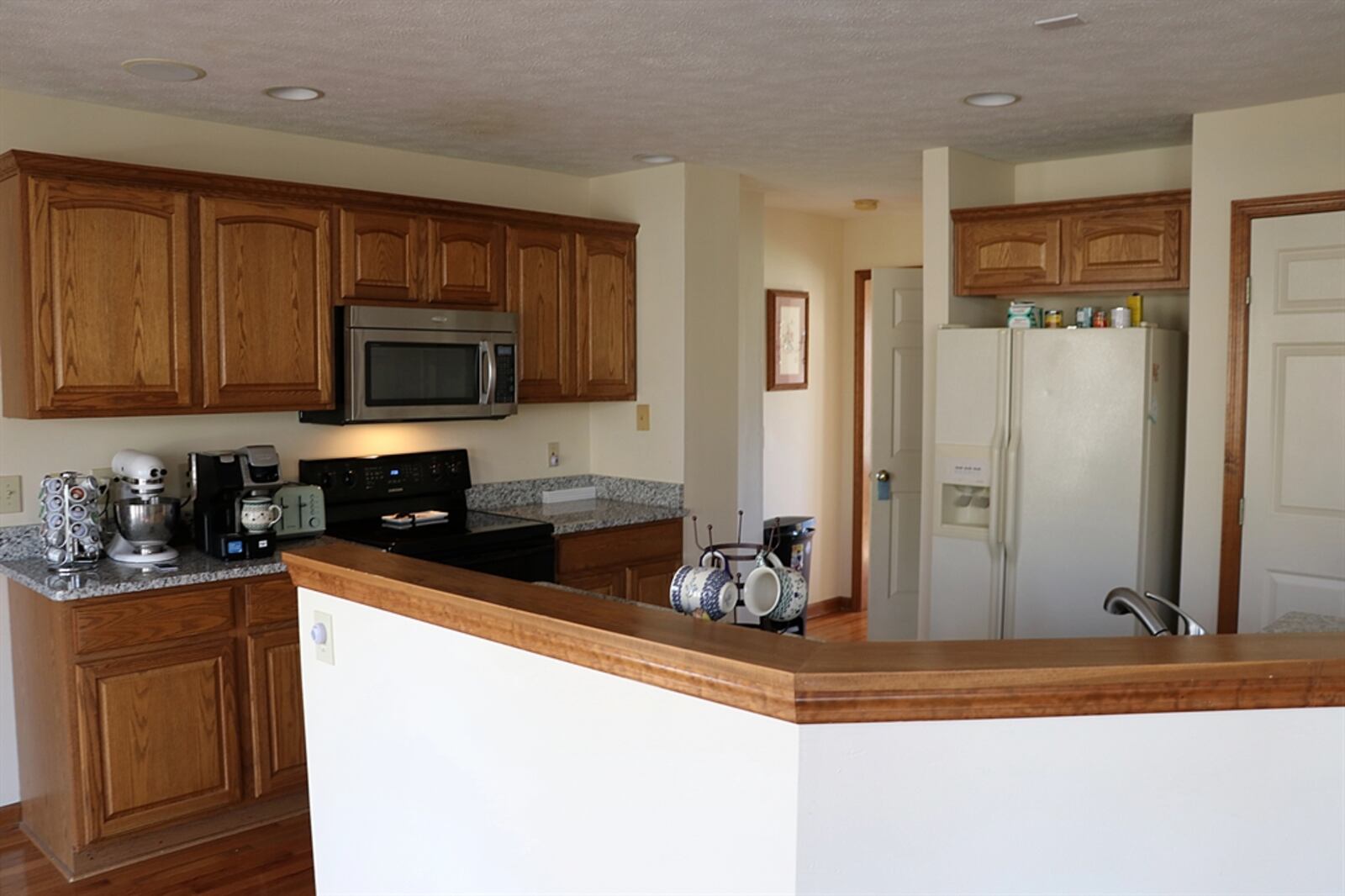 A wood-capped partial wall wraps around the kitchen and hides the granite counter with double sink from the breakfast room.