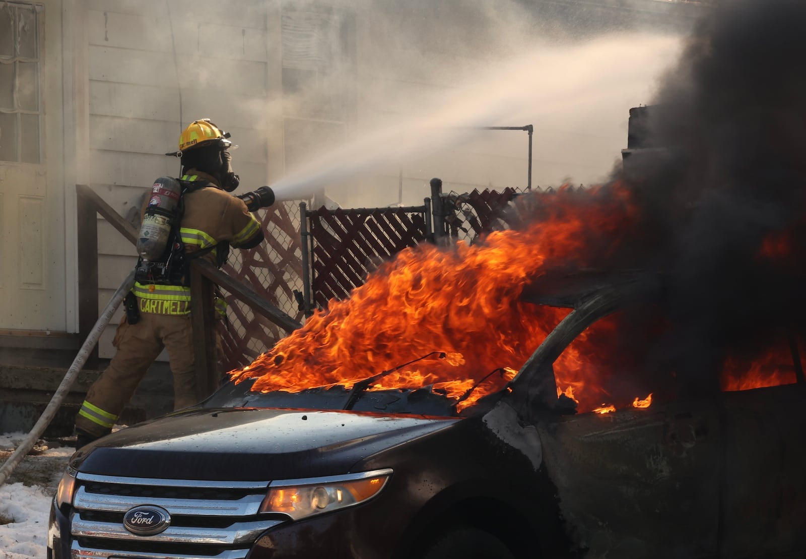 A Ford was engulfed as crews battle a large fire Tuesday, Feb. 15, 2022, involving a detached two-car garage in the 1600 block of Summit Street in Springfield. BILL LACKEY/STAFF