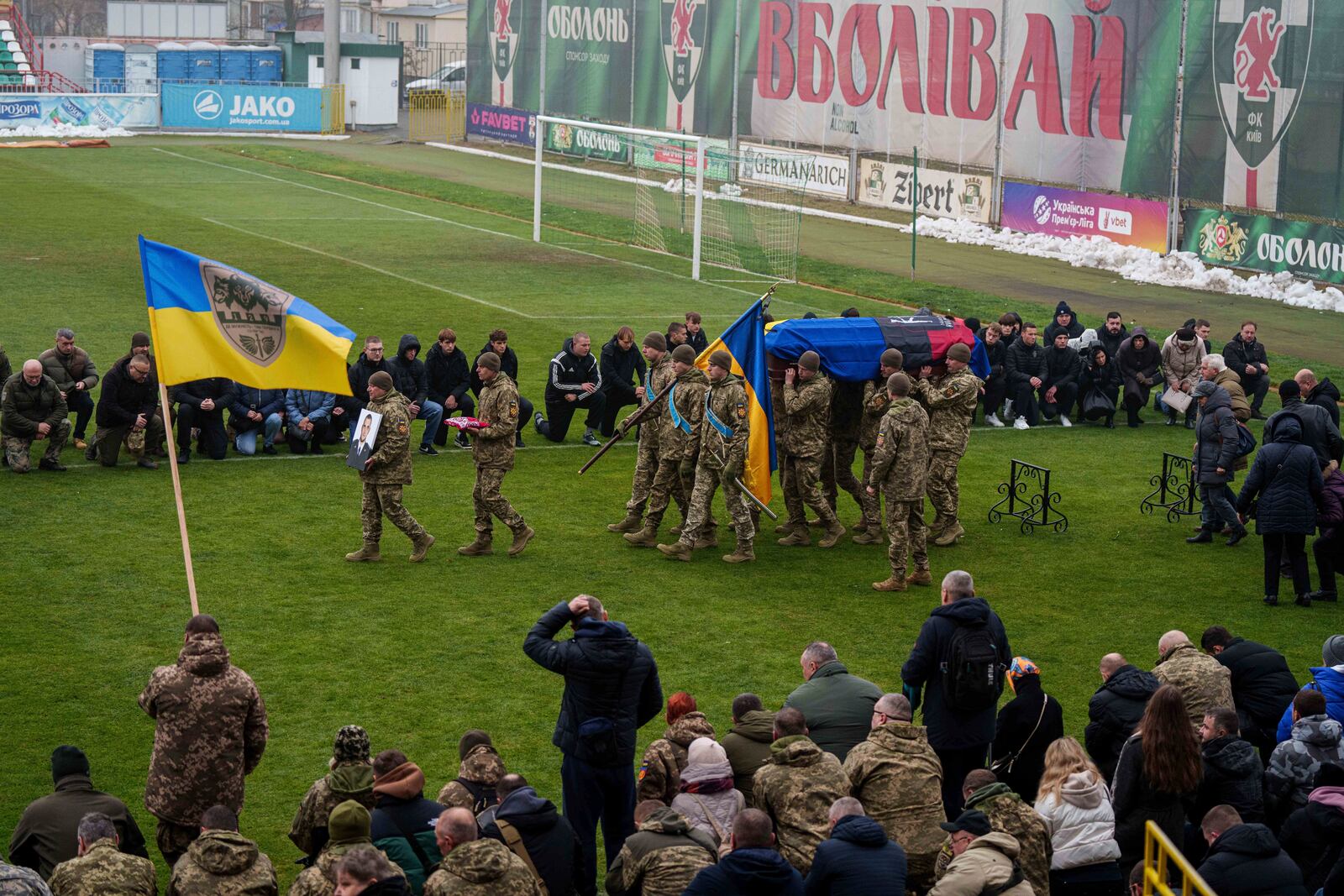 Honor Guards carry portrait and coffin of a Ukrainian officer Pavlo Vedybida aka "Obolonchik" at the Obolon Stadium in Kyiv, Ukraine, Saturday, Nov. 30, 2024. (AP Photo/Evgeniy Maloletka)