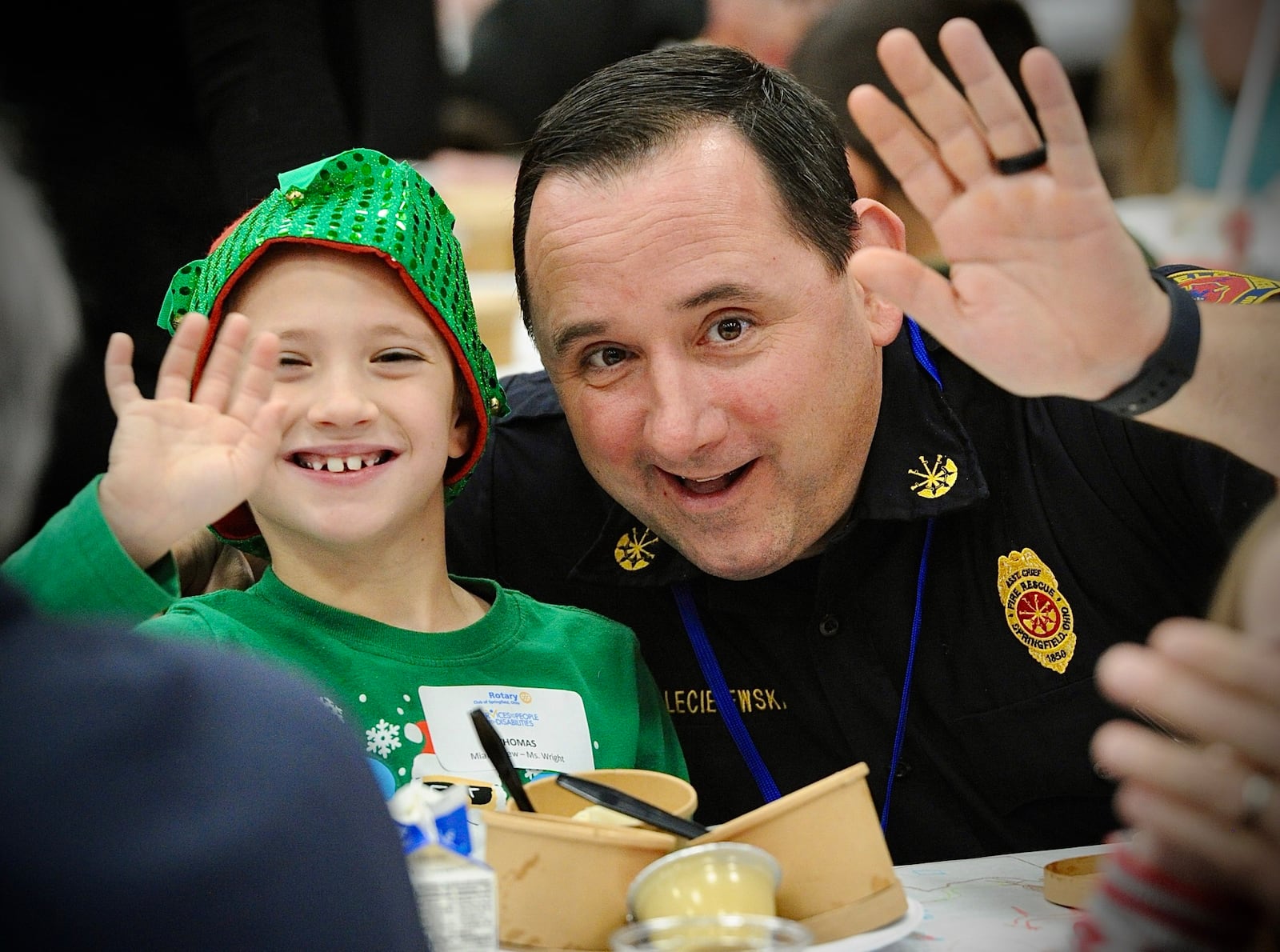 Thomas Domer, age 8, enjoys lunch with Brian Leciejewski of the Springfield Fire Division, Tuesday, December 12, 2023 at the Springfield Rotary 101st Children with Disabilities Christmas Party at the HWA center on the Wittenberg University campus. MARSHALL GORBY \STAFF