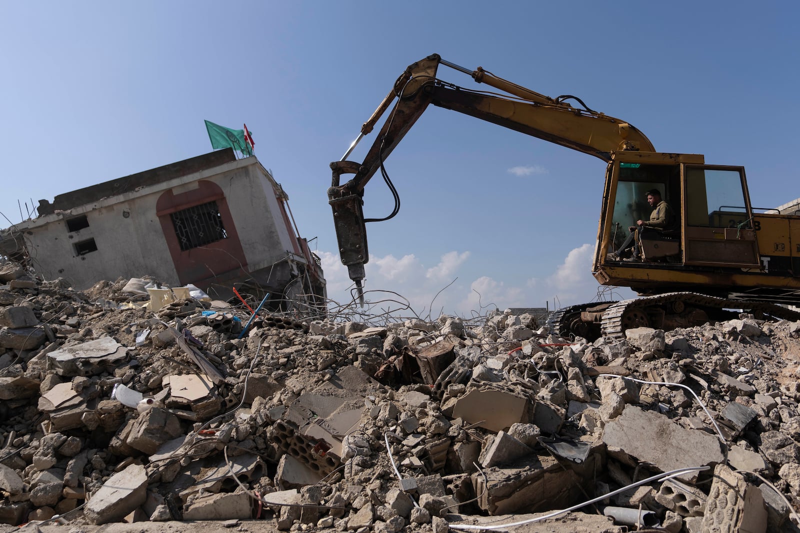 A bulldozer equipped with drill works on the rubble of destroyed houses, caused by the Israeli air and ground offensive, in the town of Khiam, southern Lebanon, Monday, Feb. 17, 2025. (AP Photo/Hassan Ammar)