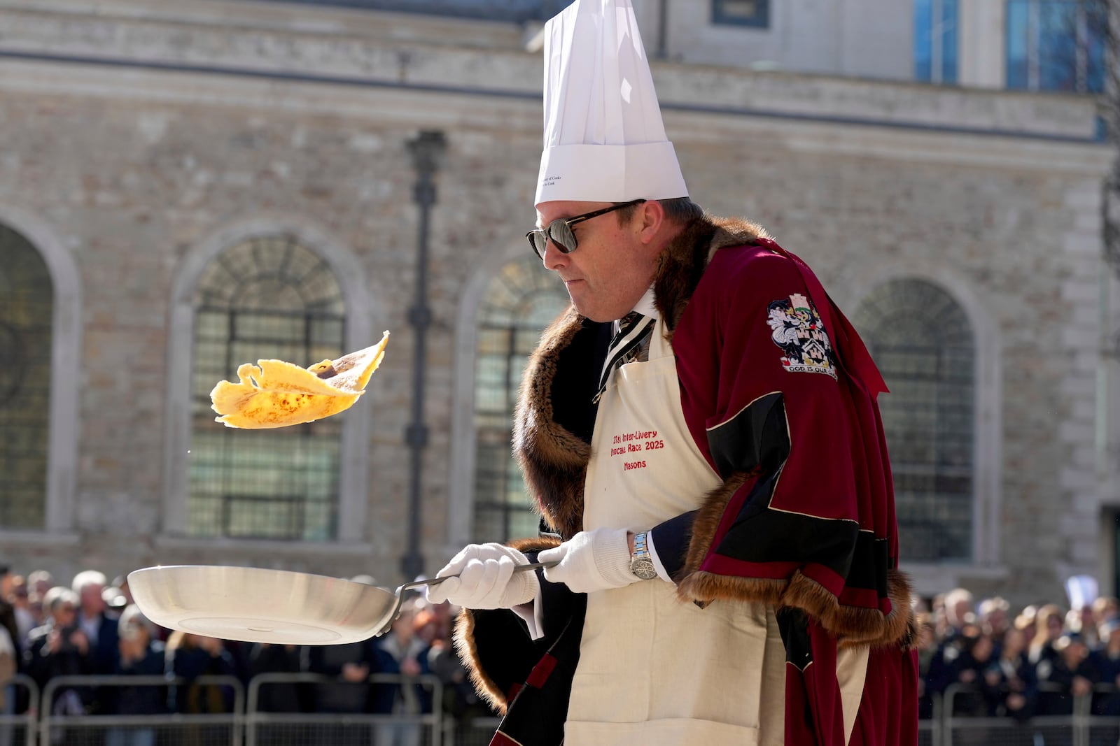 A competitor flips a pancake during a traditional pancake race by livery companies at the Guildhall in London, Tuesday, March 4, 2025.(AP Photo/Frank Augstein)