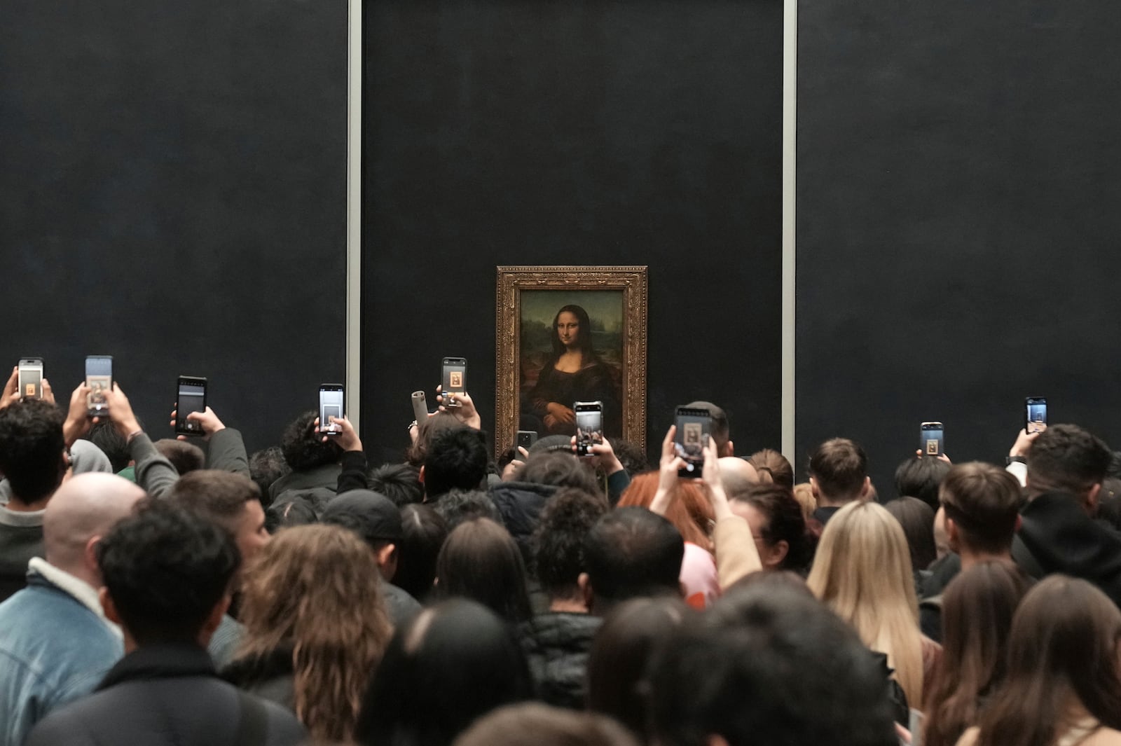 Visitors take photographs from their mobile phone of Leonardo da Vinci's painting of the Mona Lisa, at the Louvre museum, Monday, Jan. 27, 2025 in Paris. (AP Photo/Thibault Camus)