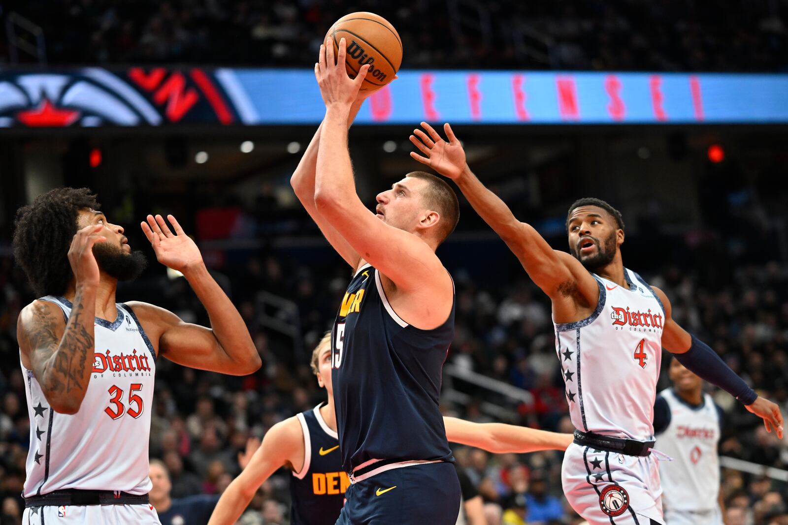 Denver Nuggets center Nikola Jokic, center, prepares to shoot a basket against Washington Wizards forward Marvin Bagley III (35) and guard Jared Butler (4) during the second half of an NBA basketball game Saturday, Dec. 7, 2024, in Washington. (AP Photo/John McDonnell)