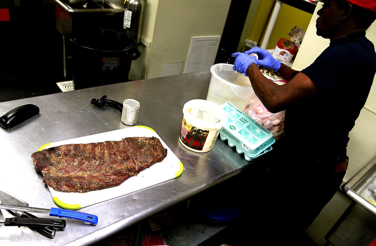 A slab of ribs waits for a customer at Al’s Smokehouse as an employee makes a batter for some chicken wings Thursday. Bill Lackey/Staff