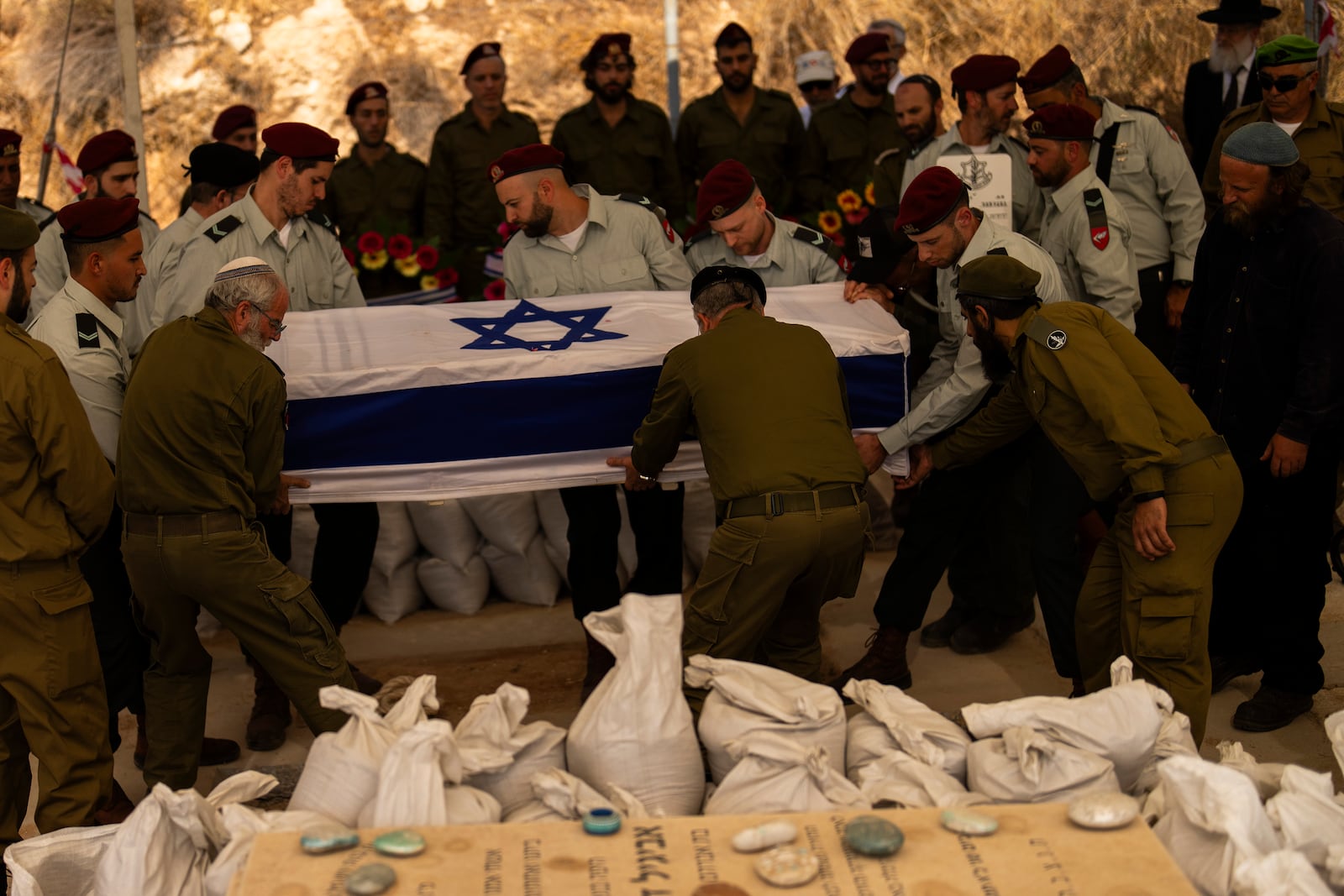 Israeli soldiers lower into the grave the flagged-covered coffin of reservist Yedidia Bloch, 31, during his funeral at Mevo Horon settlement, West Bank, Wednesday, Oct. 30, 2024. Bloch died on Tuesday 29 after he was injured in Lebanon. (AP Photo/Francisco Seco)