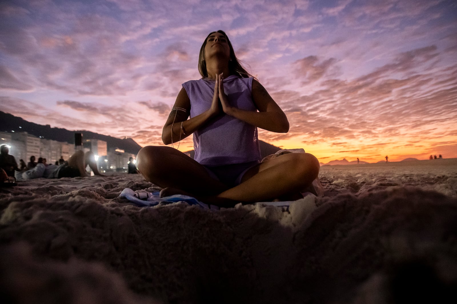 FILE - A woman sits in lotus prayer pose during the "Yoga at the Sunrise" event on Copacabana beach, in Rio de Janeiro, on June 22, 2024. (AP Photo/Bruna Prado, File)