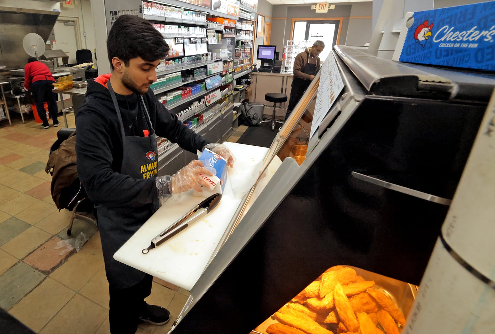 Hasan Rana serves up some Chester's Chicken for a customer Wednesday, Jan. 22, 2025 at the new Marathon/Chester's Chicken in North Hampton. BILL LACKEY/STAFF