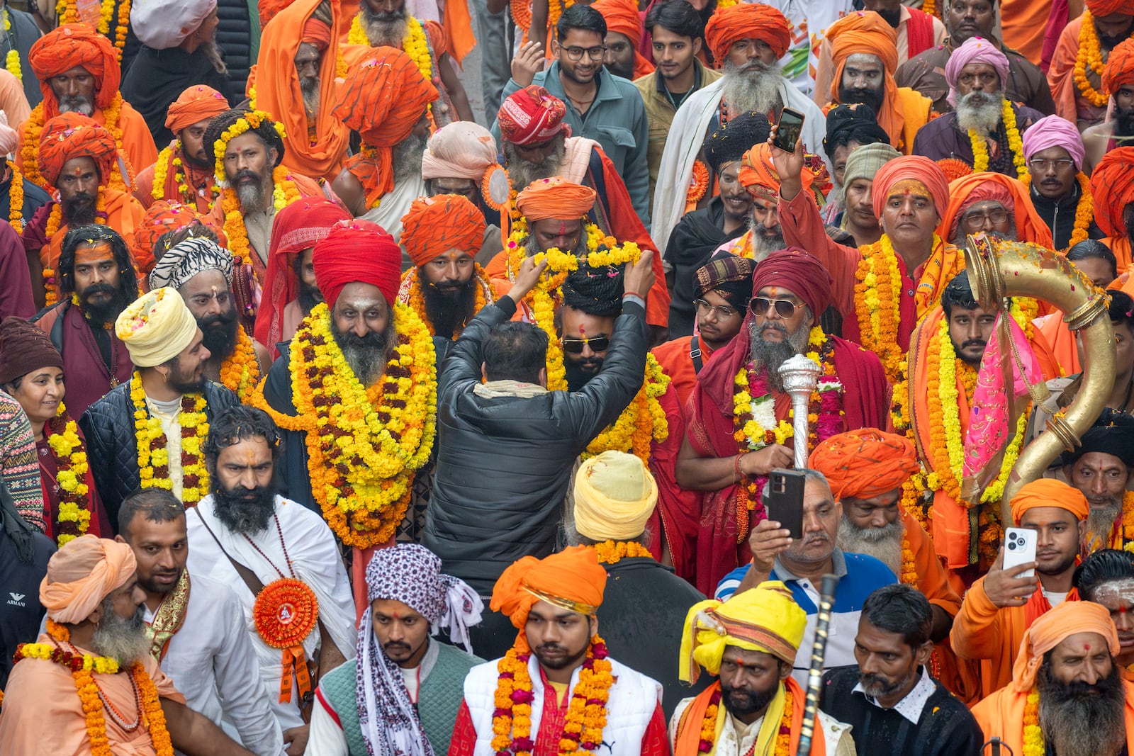 A devotee garlands a senior Hindu holy man walking in a procession, a day before the 45-day-long Maha Kumbh festival, in Prayagraj, India, Sunday, Jan. 12, 2025. (AP Photo/Ashwini Bhatia)