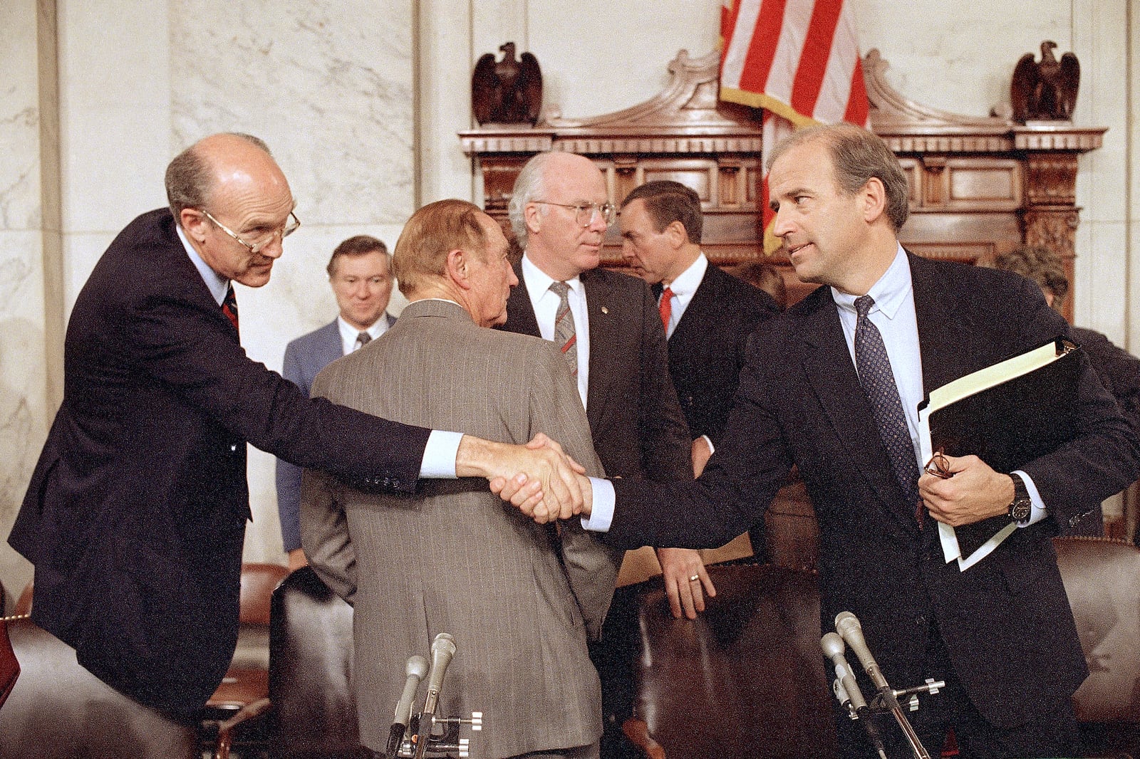 FILE - Senate Judiciary Chairman Joseph Biden, D-Del., right, shakes hands with Sen. Alan Simpson, R-Wyo., after the committee voted not to recommend the confirmation of Supreme Court nominee Robert Bork, during a meeting on Capital Hill in Washington, Oct. 7, 1987. Standing behind, from left center are Sens. Strom Thurmond, R-S.C., back to camera, and Patrick Leahy, D-Vt. Simpson has died at age 93. (AP Photo/John Duricka, File)