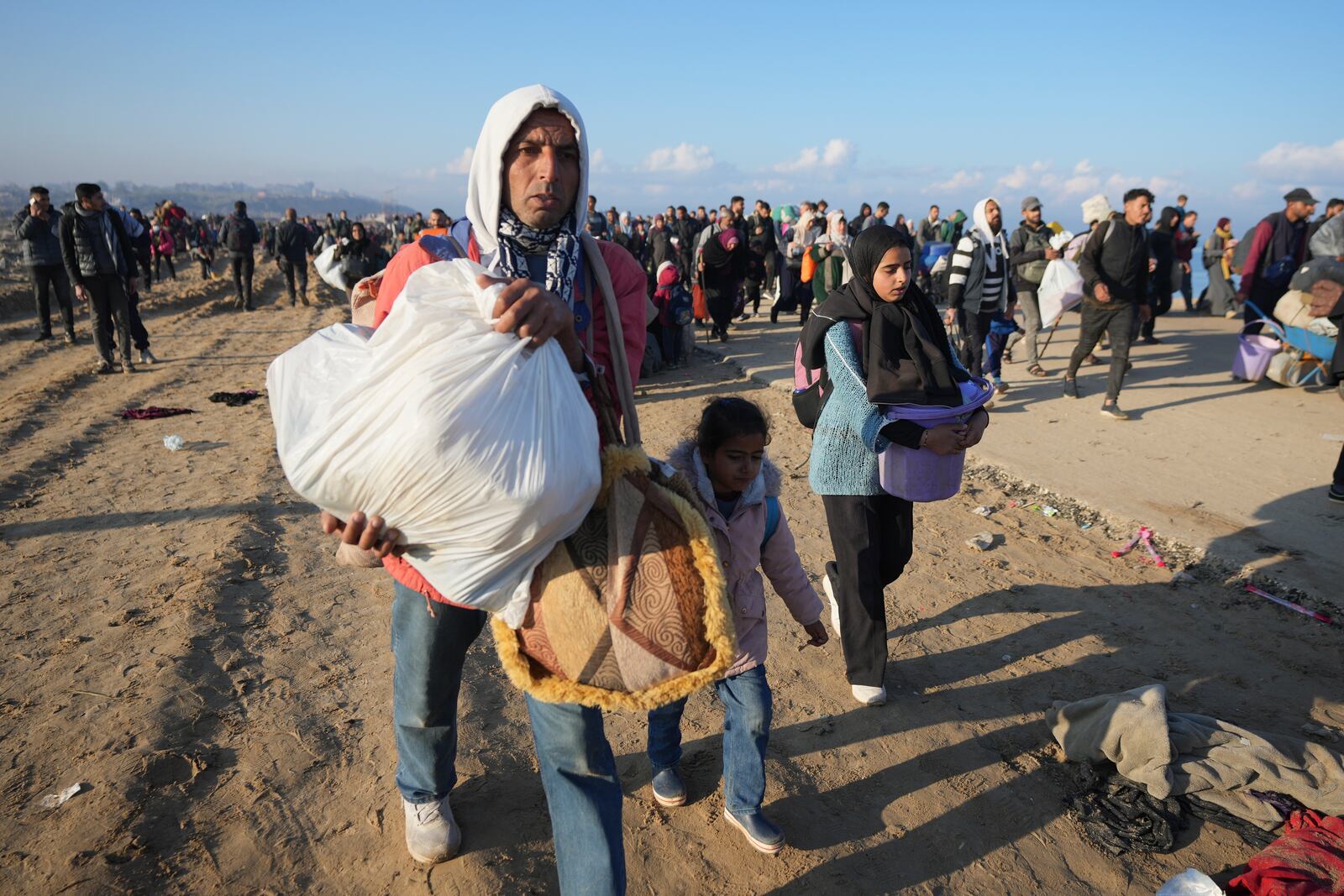 Ne'man Abu Jarad walks with his family as thousands of displaced Palestinians return to their homes in the northern Gaza Strip, following Israel's decision to allow them to go back for the first time since the early weeks of the 15-month war with Hamas, Monday, Jan. 27, 2025. (AP Photo/Abdel Kareem Hana)