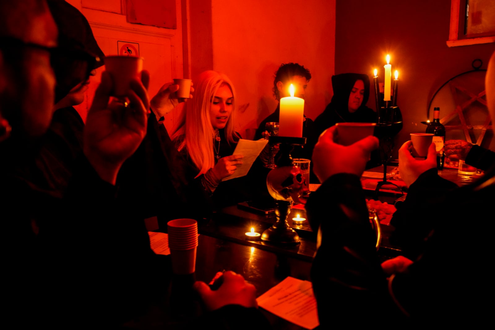 Members of The Temple of Satan: Satanists and Luciferians of Chile, drink wine at the start of a monthly ceremony in Santiago, Friday, Sept. 27, 2024. (AP Photo/Esteban Felix)