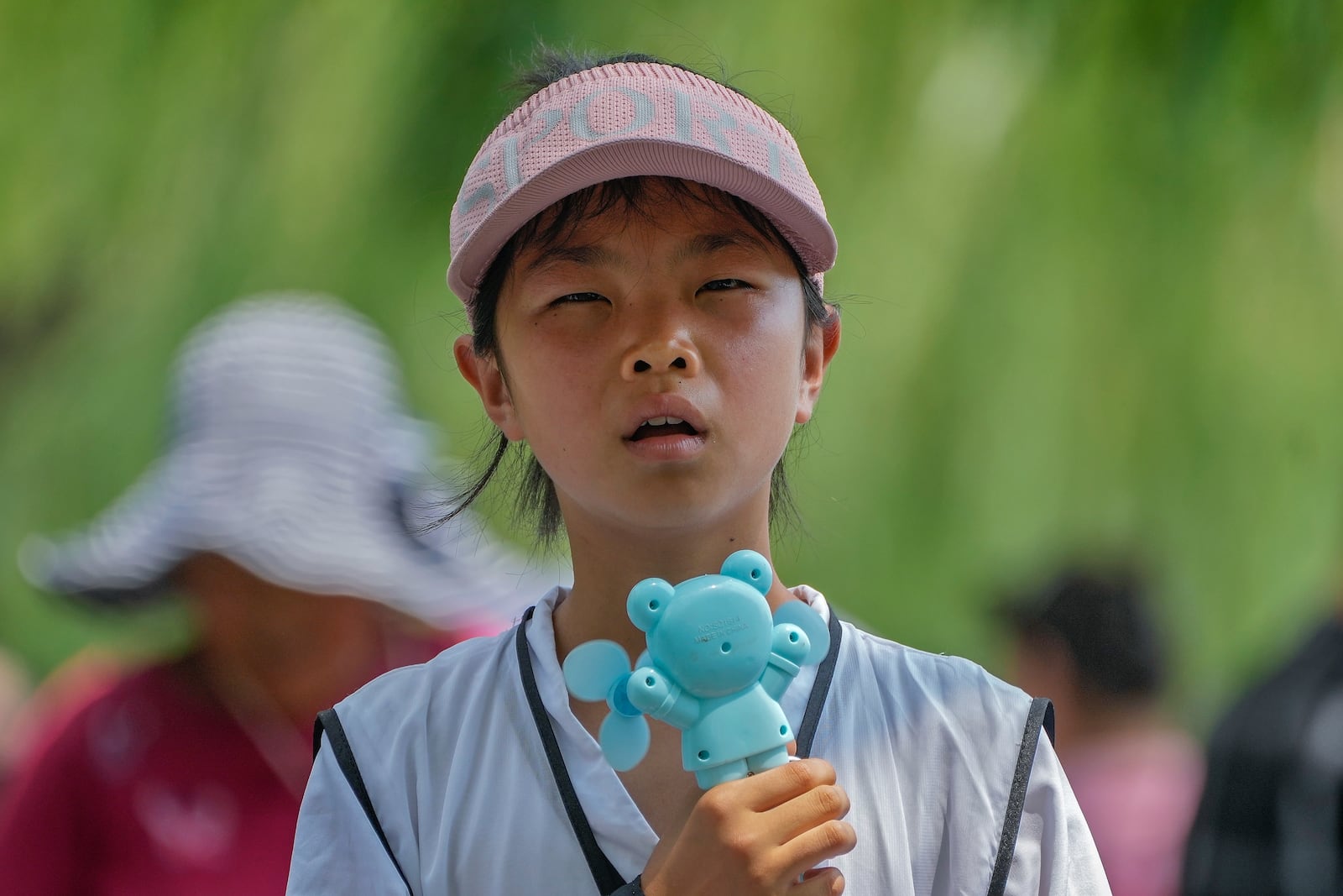 FILE - A child holds an electric fan as they react to the heat during a visit to the Forbidden City in Beijing, July 8, 2024. (AP Photo/Andy Wong, File)