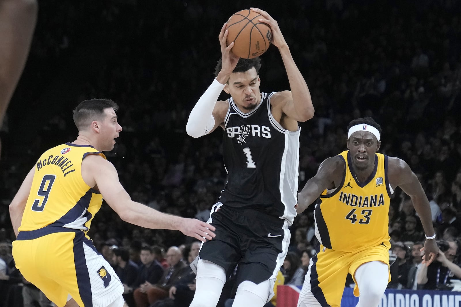 San Antonio Spurs center Victor Wembanyama (1) drives to the basket against Indiana Pacers guard T.J. McConnell (9) and forward Pascal Siakam (43) during the second half of a Paris Games 2025 NBA basketball game in Paris, Thursday, Jan. 23, 2025. (AP Photo/Thibault Camus)