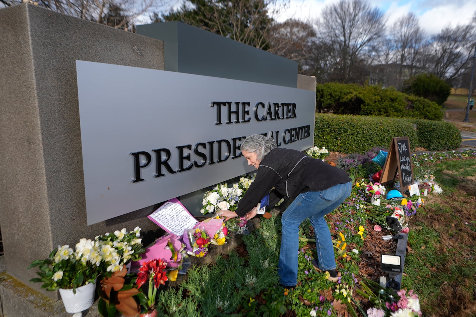 Carter Center volunteer Denise Bomberger places flowers at the entrance to the Jimmy Carter Presidential Center Tuesday, Dec. 31, 2024, in Atlanta. Carter died Sunday at he age of 100. (AP Photo/John Bazemore )