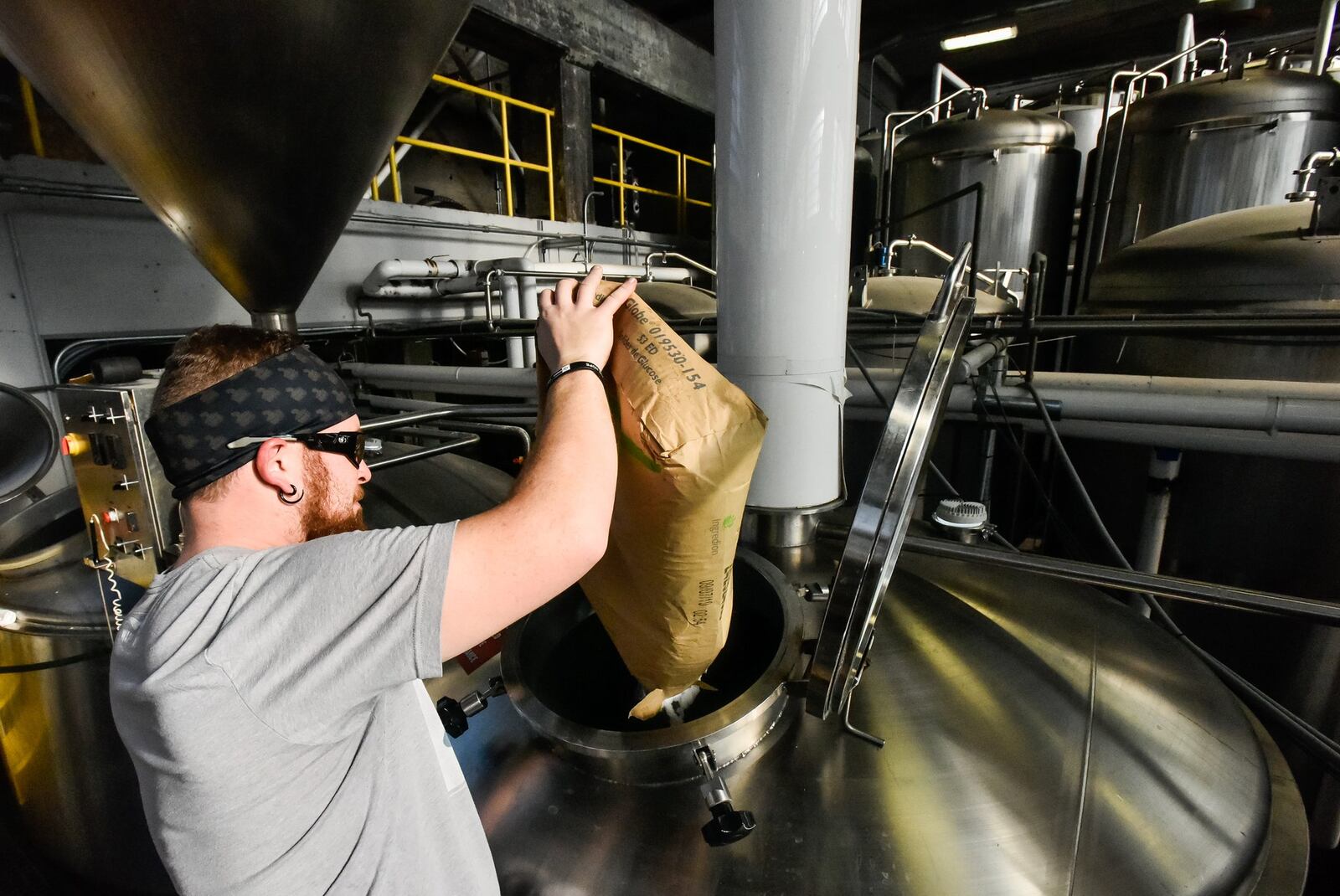 Brewer Josh Hoopes dumps in ingredients for a new batch of Whiskey Rebellion beer at Warped Wing Brewing Company Thursday, Dec. 19, 2019 on Wyandot Street in Dayton. NICK GRAHAM/STAFF