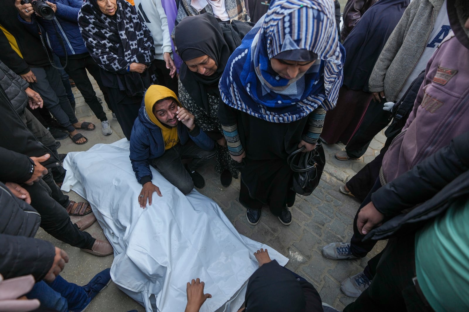 Relatives and neighbours mourn over the body of one of the victims of an Israeli strike on a hom4 late Saturday as they are prepared for the funeral outside the Al-Aqsa Martyrs Hospital in Deir al-Balah Sunday, Dec. 22, 2024. At least eight people were killed according to the hospital which received the bodies.(AP Photo/Abdel Kareem Hana)