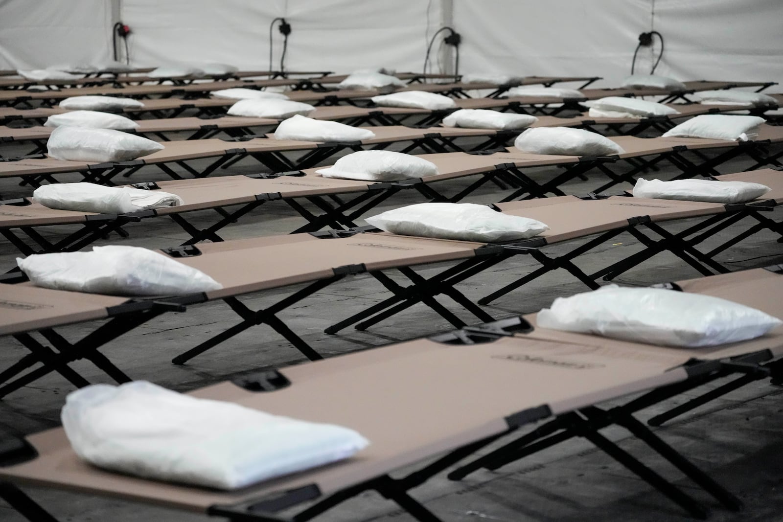 FILE - Bags containing bedding are placed on cots inside the dormitory tent during a tour of a shelter New York City that is setting up to house up to 1,000 migrants, in the Queens borough of New York, Aug. 15, 2023. (AP Photo/Mary Altaffer, File)