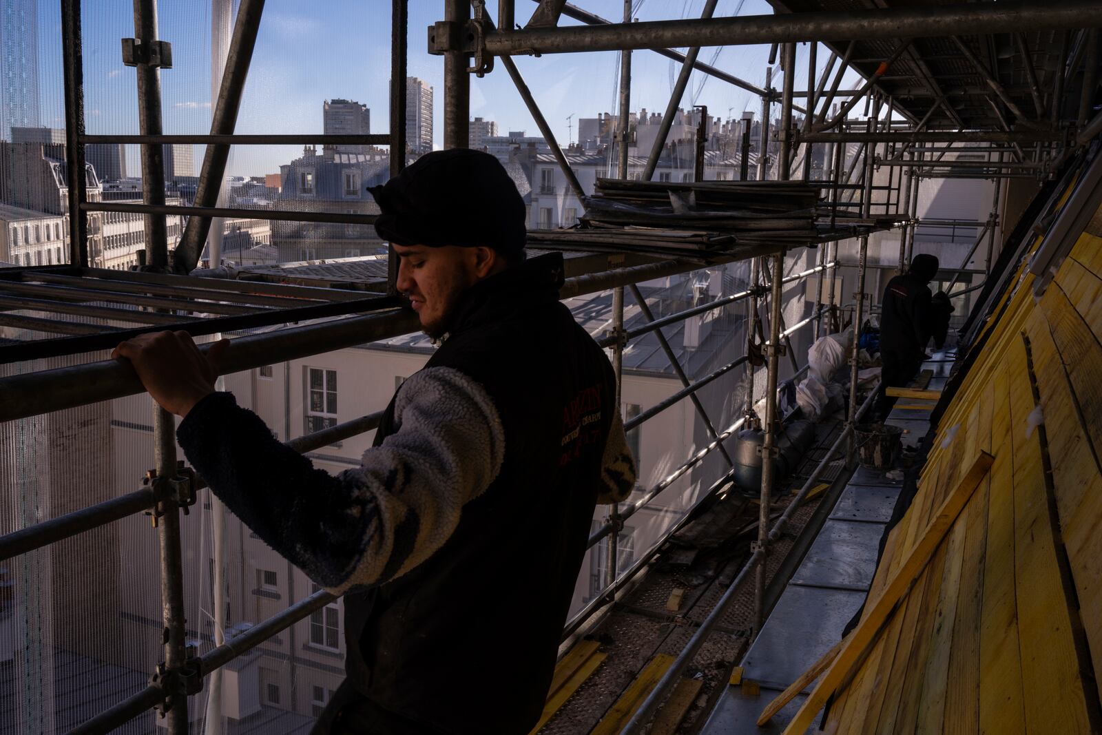 Roofers work on a building in Paris, Wednesday, Nov. 20, 2024. (AP Photo/Louise Delmotte)