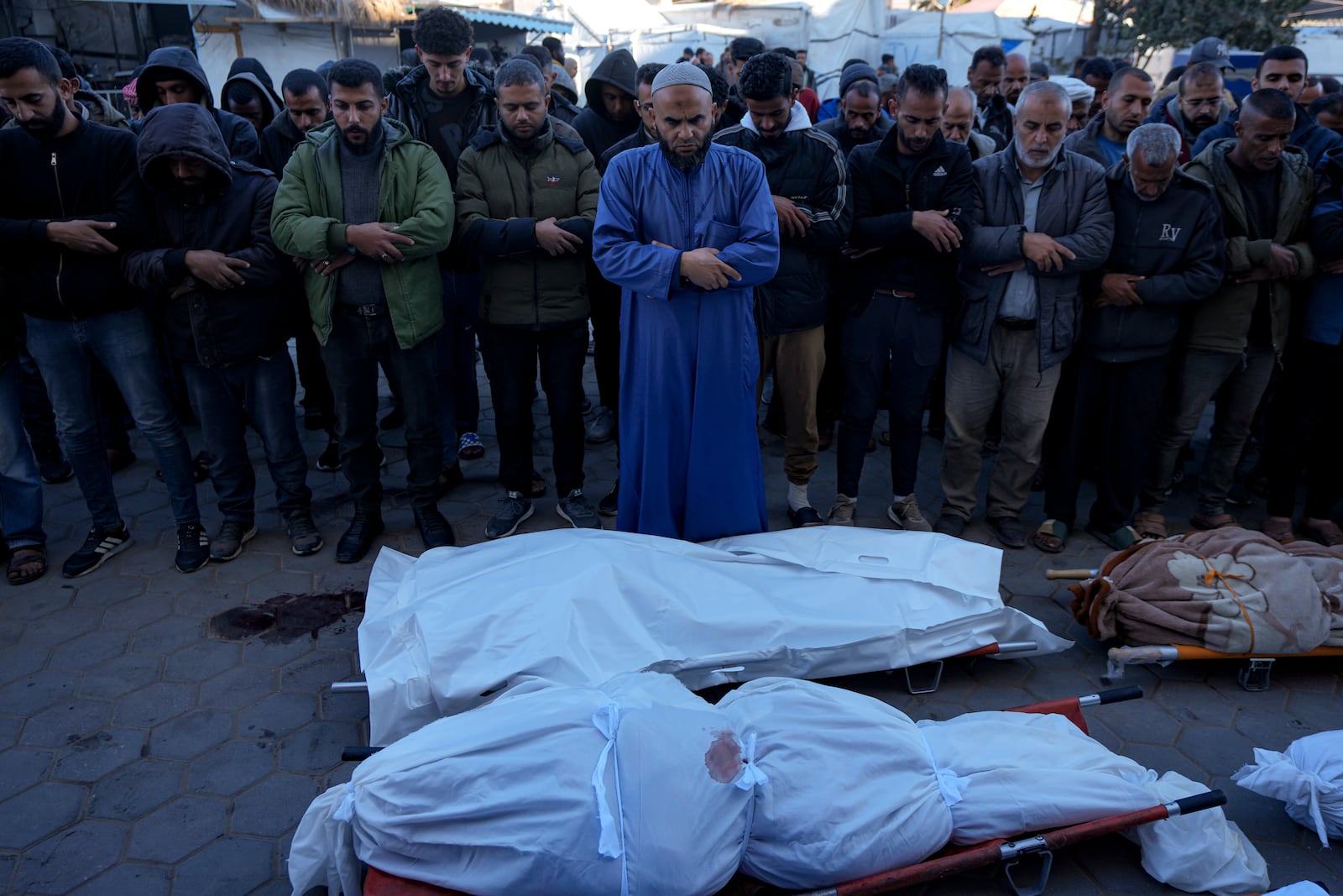 Palestinians pray next to the bodies of their relatives killed in the Israeli bombardment of the Gaza Strip, at a hospital in Deir al-Balah, Sunday, Dec. 15, 2024. (AP Photo/Abdel Kareem Hana)