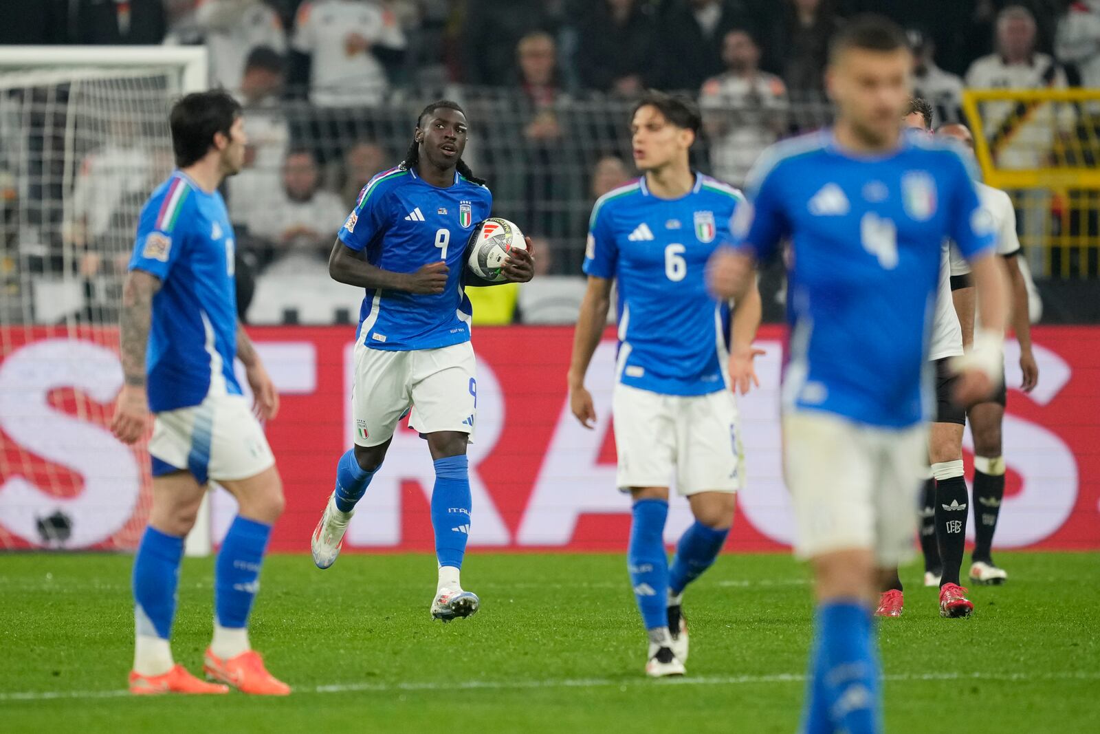 Italy's Moise Kean, second from left, celebrates after scoring his side's first goal during the Nations League quarterfinal second leg soccer match between Germany and Italy at the Signal-Iduna Park in Dortmund, Germany, Sunday, March 23, 2025. (AP Photo/Martin Meissner)