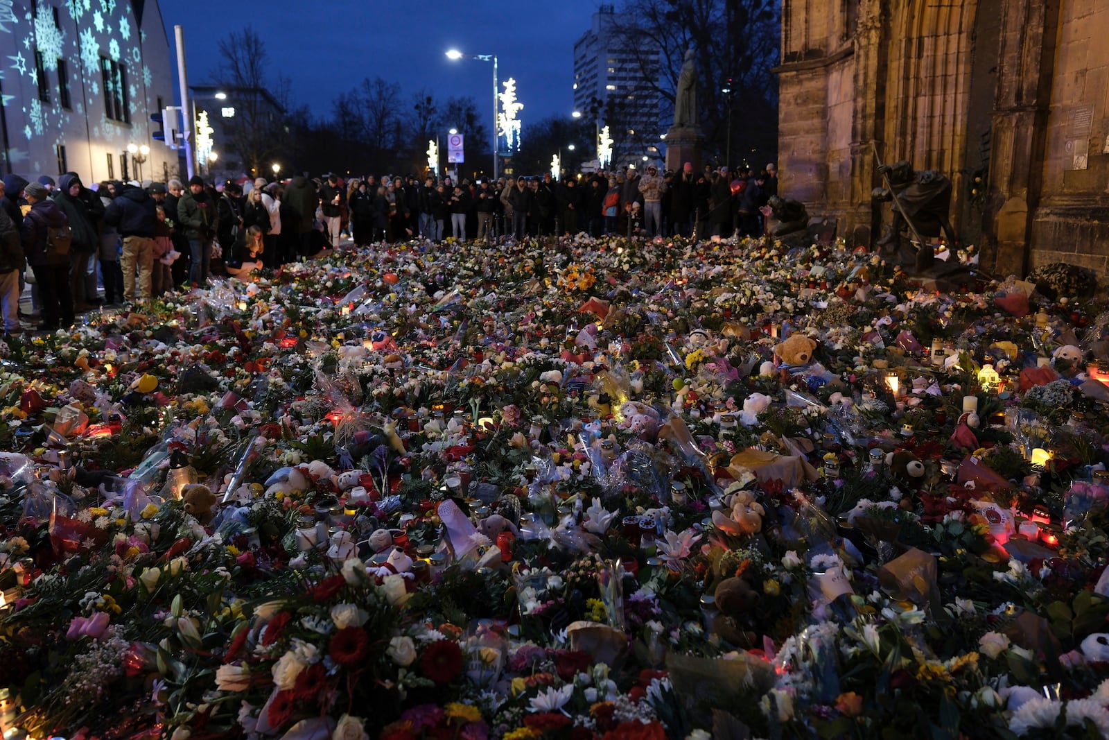 Flowers, candles and wide offerings of mourning in front of St. John's Church, close to the Christmas market where a car drove into a crowd on Friday evening, in Magdeburg, Germany, Monday, Dec. 23, 2024. (Sebastian Willnow/dpa via AP)