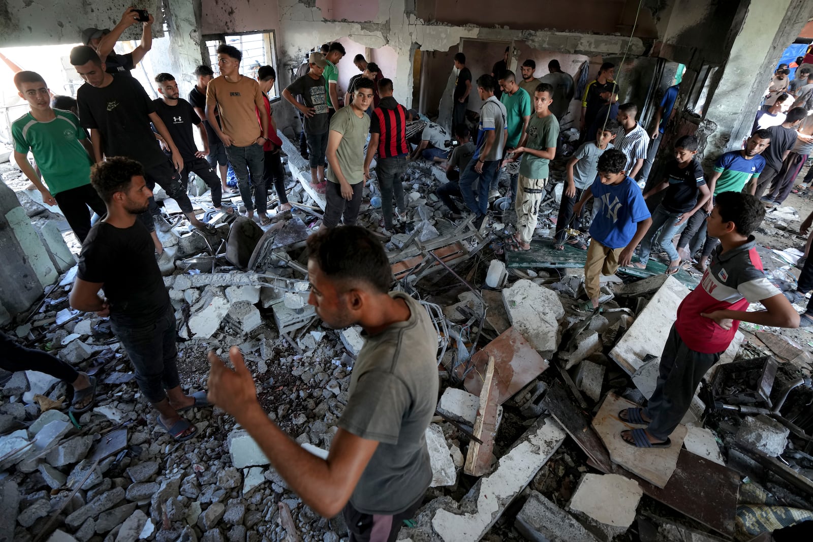 Palestinians search for the bodies of their relatives killed in an Israeli bombardment of a school in Deir al-Balah, central Gaza Strip, Thursday, Oct. 10, 2024. (AP Photo/Abdel Kareem Hana)