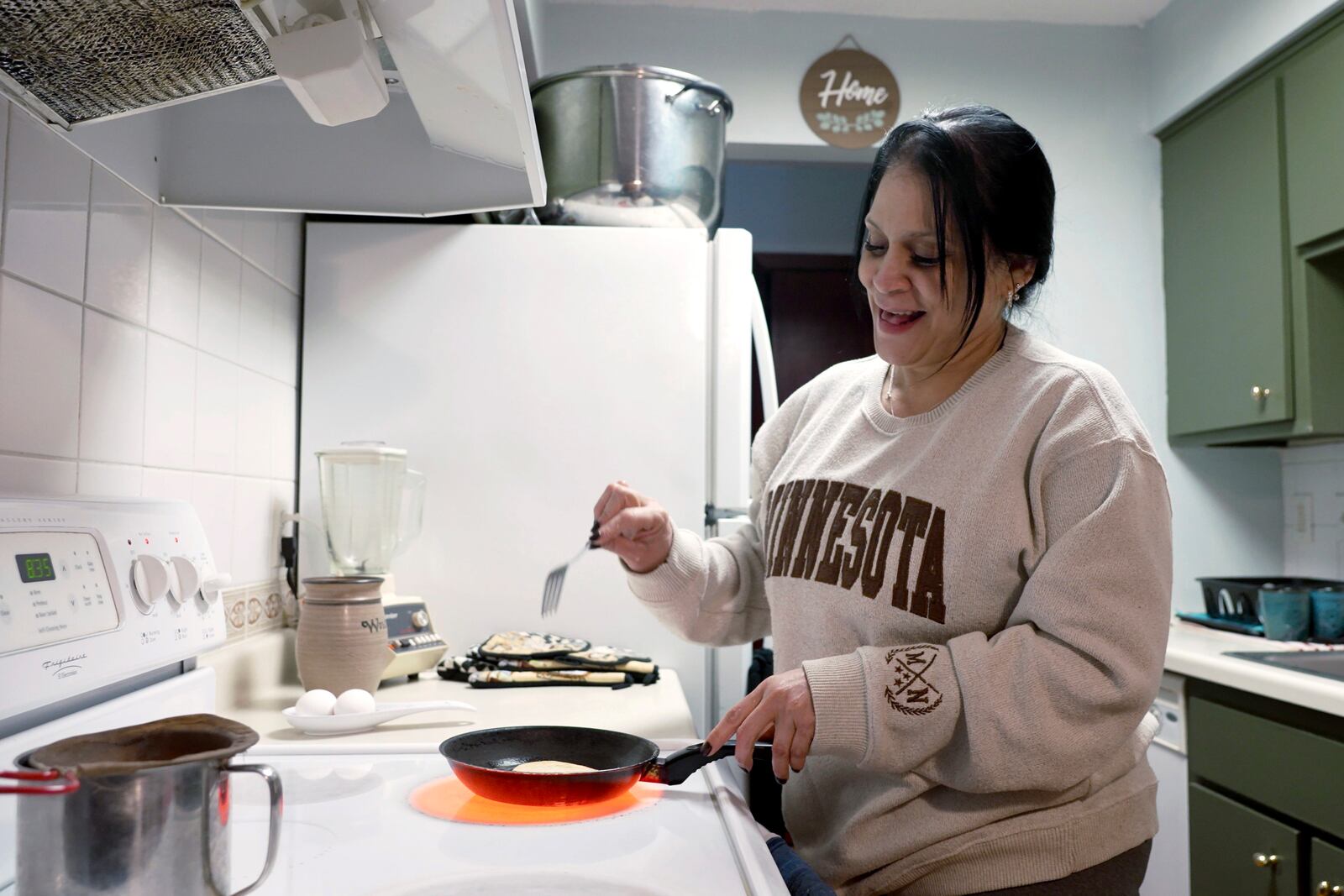 Marlenia Padron, a Venezuelan in the United States on temporary protected status – which was recently curtailed and set to expire in April – fries arepas in her home in Hopkins, Minn., on Thursday, Feb. 13, 2025. (AP Photo/Mark Vancleave)