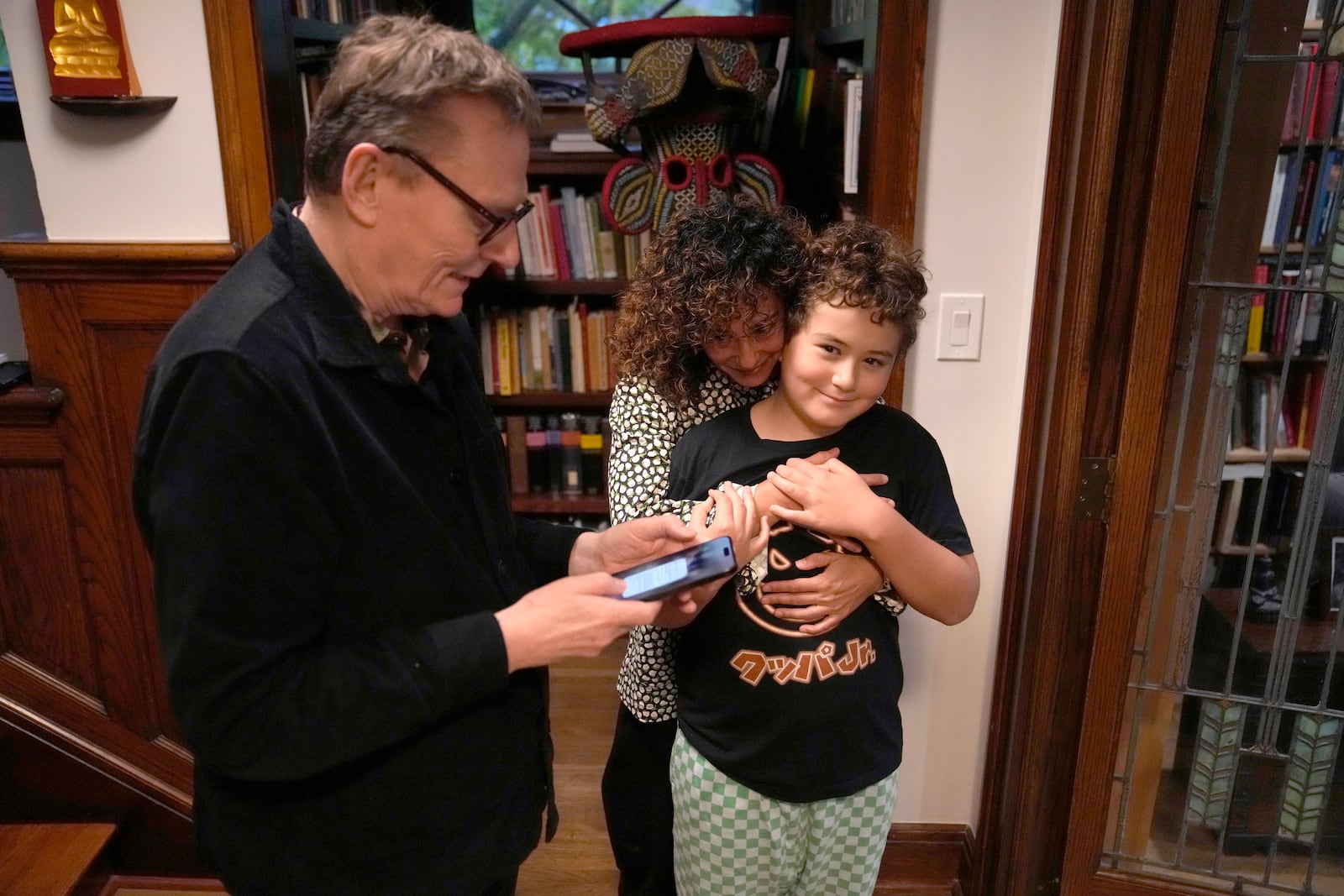 Nobel prize winner in Economics, James A. Robinson, looks over a selfie he made for the Nobel Foundation with his wife Dr. Maria Angelica Bautista, and son Adrian at their home in the Hyde Park neighborhood of Chicago, Monday, Oct. 14, 2024. (AP Photo/Charles Rex Arbogast)