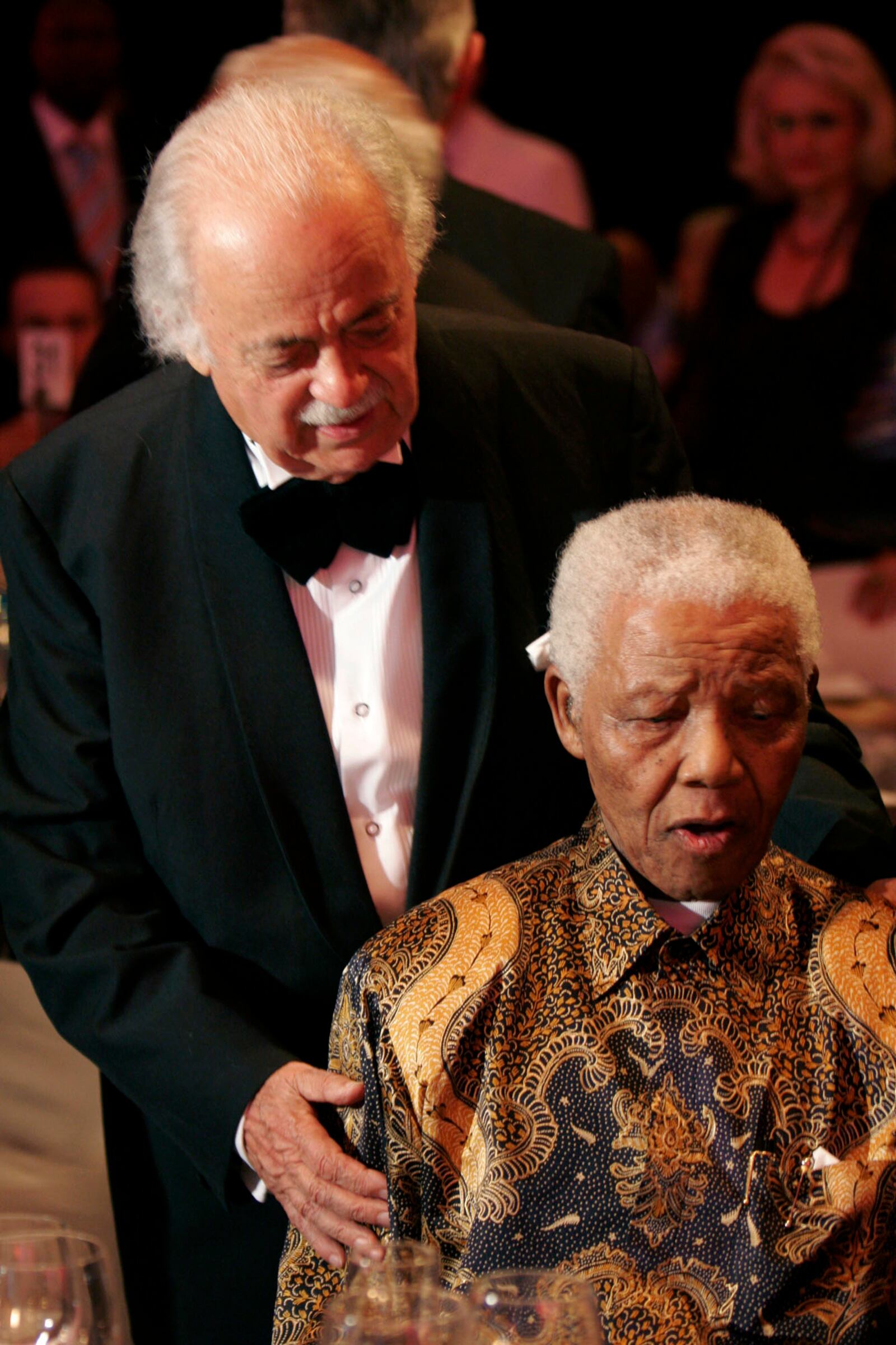 FILE — In this Wednesday Nov. 12, 2008 file photo George Bizos, left, anti-apartheid activist, and life-long friend and lawyer of Nelson Mandela, right, arrives for his 80th birthday party in Johannesburg, South Africa.  Bizos died Wednesday Sept. Sept. 9, 2020, aged 92. (AP Photo/Denis Farrell, FILE)