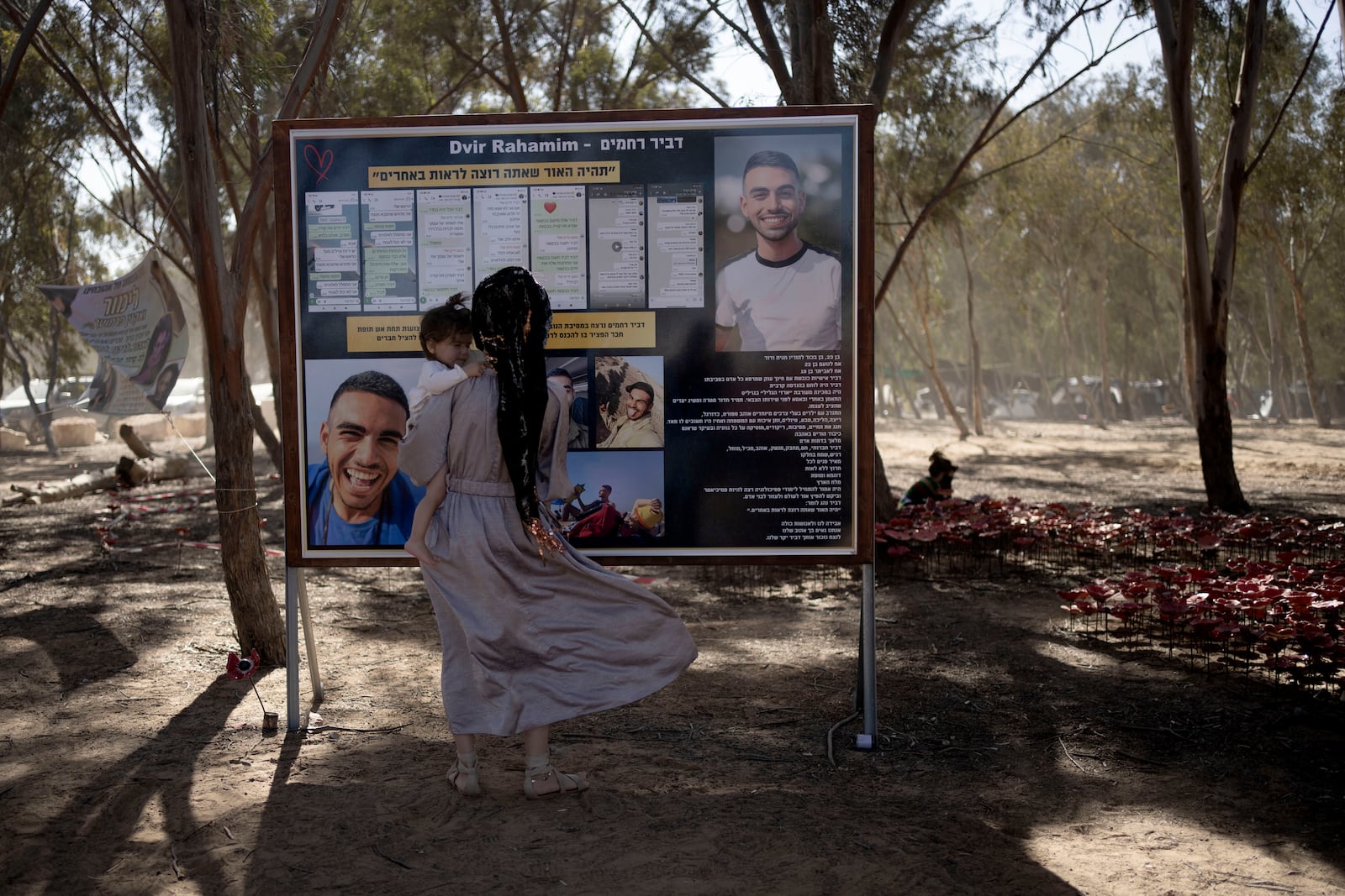 A woman reads a memorial poster at the site of the Nova music festival, where hundreds of revelers were killed or kidnapped by Hamas, on the Jewish holiday of Simchat Torah, marking one year in the Hebrew calendar since the attack, near Kibbutz Re'im, southern Israel near the Gaza Strip, Thursday, Oct. 24, 2024. (AP Photo/Maya Alleruzzo)