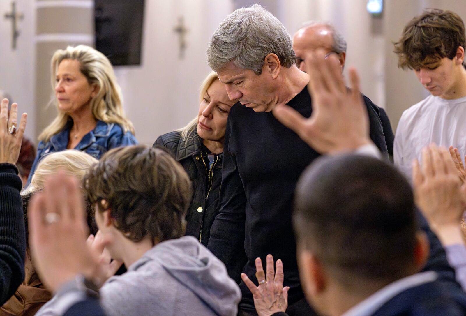 Pacific Palisades residents affected by the fires stand while parishioners, along with members of the Corpus Christi Catholic Church, pray for them at St. Monica Catholic Church during a service in Santa Monica, Calif., Sunday, Jan. 12, 2025. (Mindy Schauer/The Orange County Register via AP)