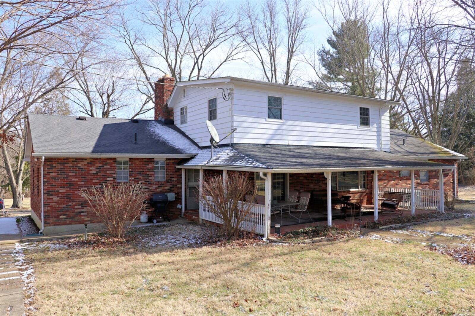 A large covered rear patio overlooks the tree-lined property, which also includes two garden barns.