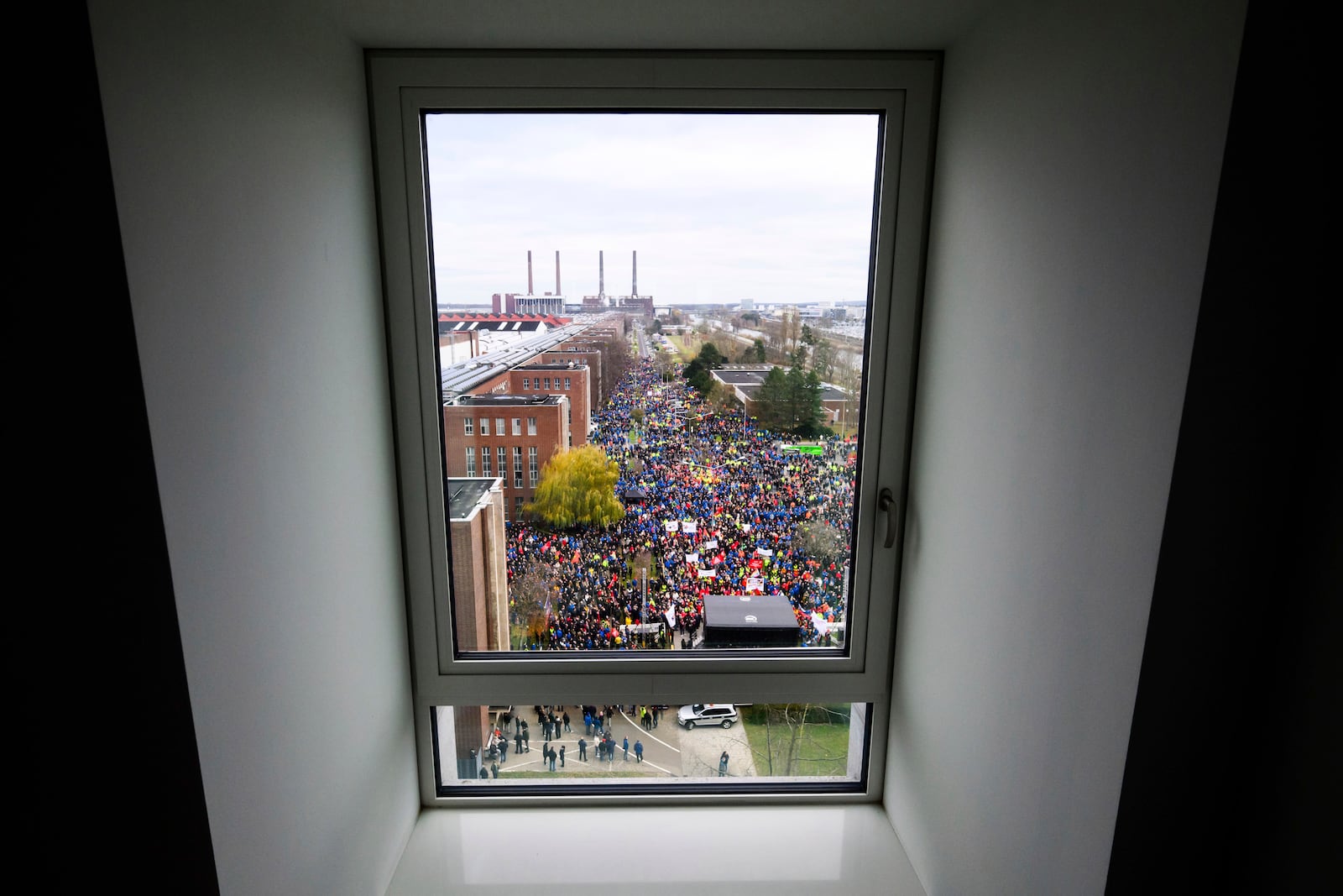 Volkswagen workers are seen through a window as they attend at a rally during at nationwide warning Volkswagen workers' strike, on the grounds of the main Volkswagen plant in Wolfsburg, Germany, Monday, Dec. 2, 2024. (Julian Stratenschulte/Pool Photo via AP)