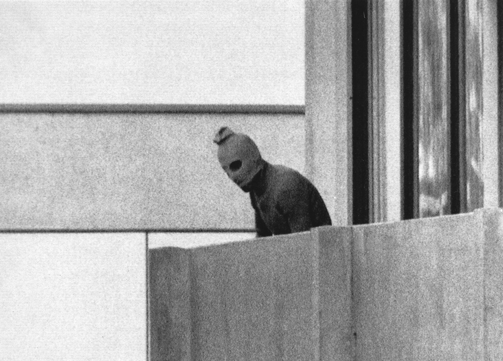 FILE - A member of the Arab Commando group which seized members of the Israeli Olympic Team at their quarters appears with a hood over his face on the balcony of the village building where the commandos held members of the Israeli team hostage, at the Munich Olympic Village, on Sept. 5, 1972. A panel of historians set up to review the 1972 attack on the Munich Olympics is starting its three-year mission to reappraise what happened before, during and after the events of five decades ago on Tuesday, the German government said. (AP Photo/Kurt Strumpf, File)