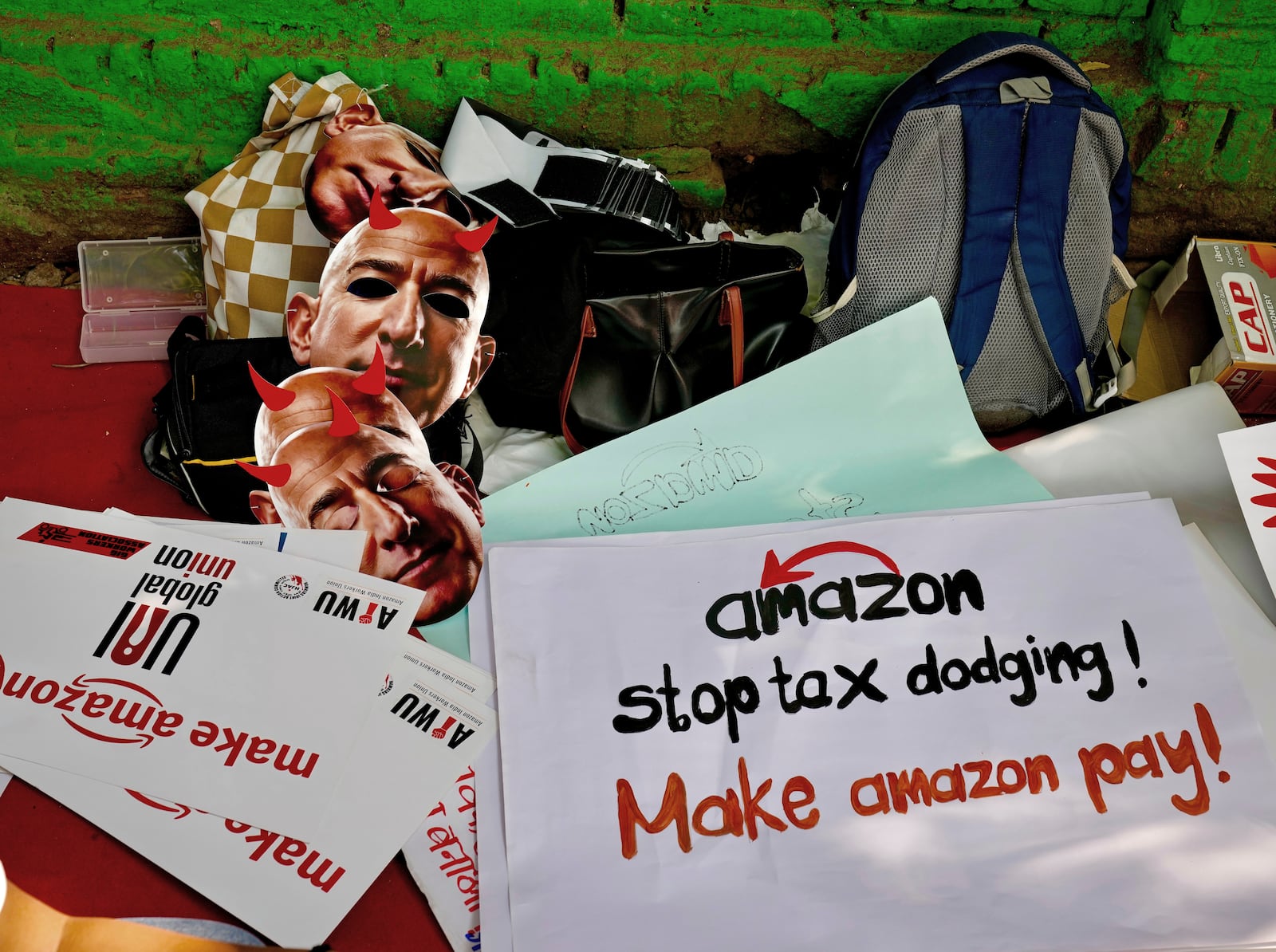 Paper masks in the likeness of Amazon's Jeff Bezos, and banners wait to be distributed to warehouse workers and delivery drivers as they stage a protest against the Seattle-based company, demanding higher wages and better working conditions, in New Delhi, India, Friday, Nov. 29, 2024. (AP Photo/Manish Swarup)