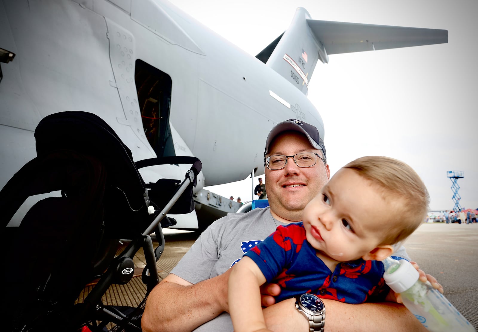 Ben Kerchner and his 10-month-old son Daniel hang out under the wing of a C-17 aircraft Sunday, June 23, 2024 at the Dayton Air Show. MARSHALL GORBY \STAFF