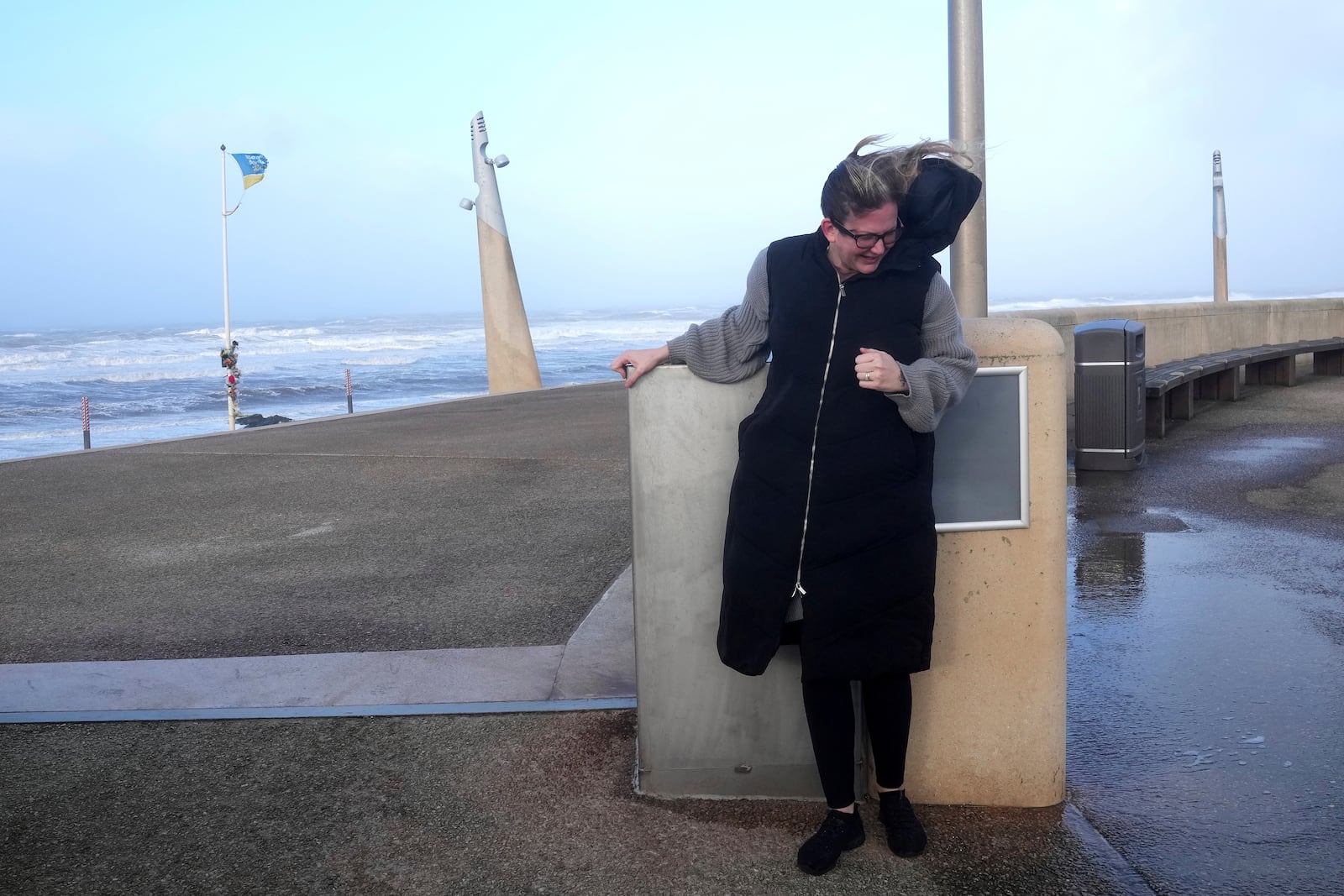 A woman holds onto a wall to brave the wind as Storm Eowyn hits the country in Cleveleys, near Blackpool, England, Friday, Jan. 24, 2025.(AP Photo/Jon Super)