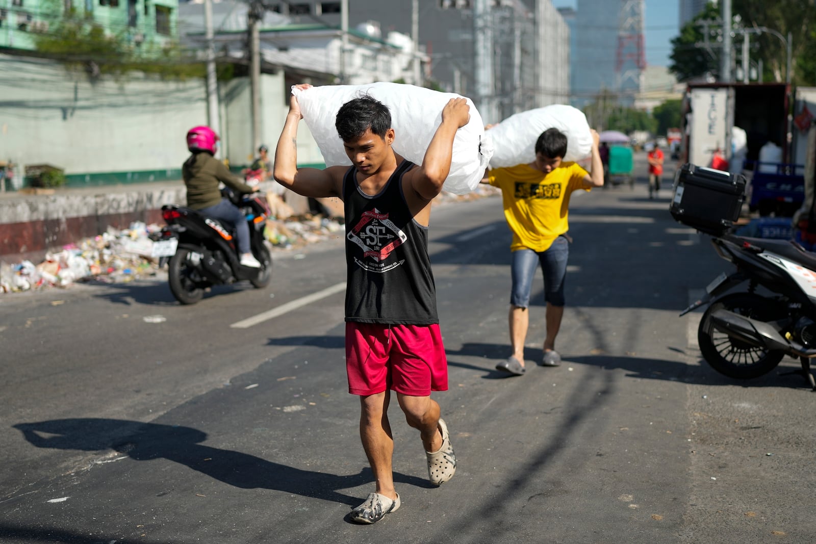 FILE - Men deliver sacks of ice cubes as demand remains high due to hot temperatures in Quezon city, Philippines on April 24, 2024. (AP Photo/Aaron Favila, File)