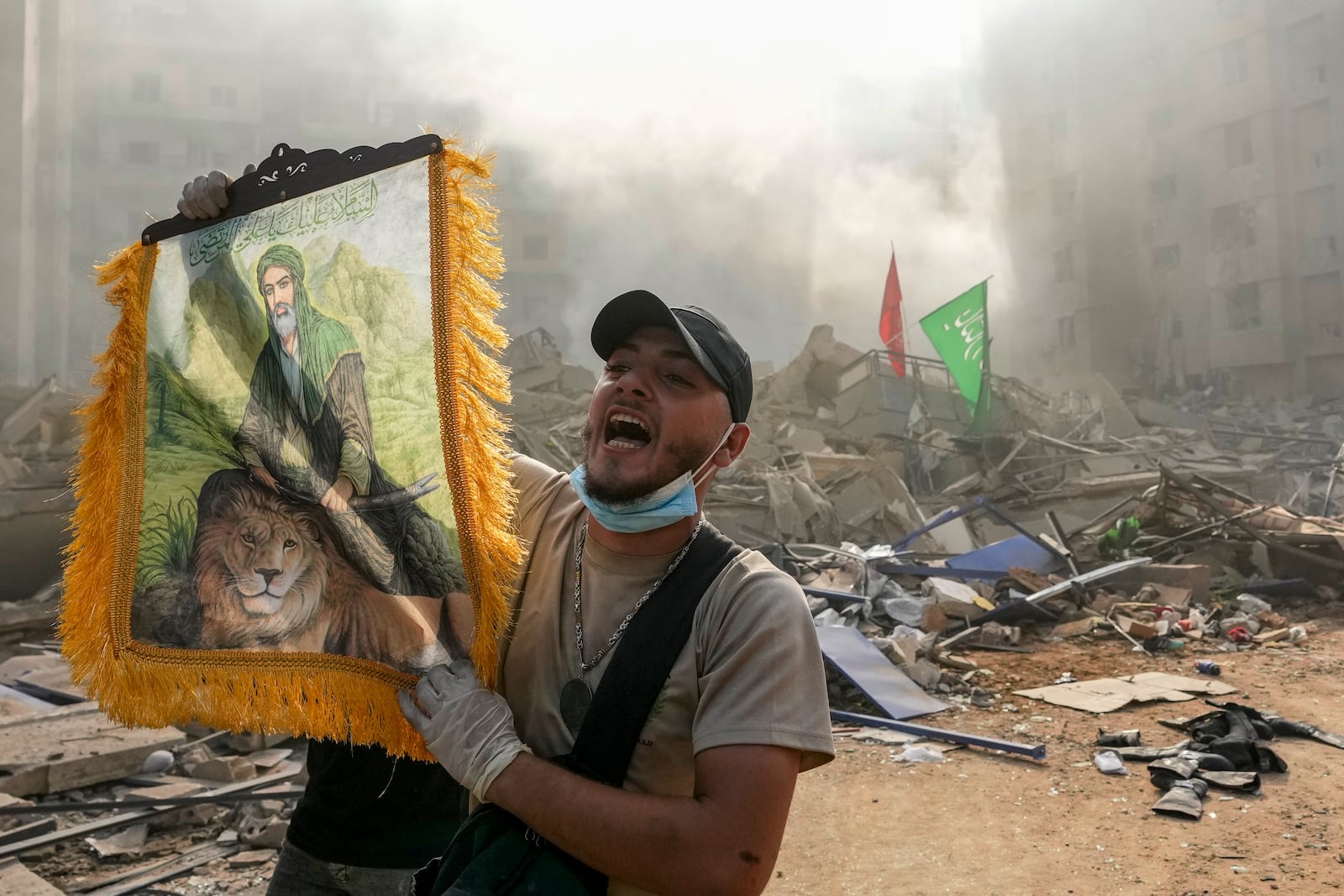 A man shouts slogans as he holds a picture depicting Imam Ali at the site of an Israeli airstrike in Dahiyeh, Beirut, Lebanon, Friday, Nov. 1, 2024. (AP Photo/Hassan Ammar)