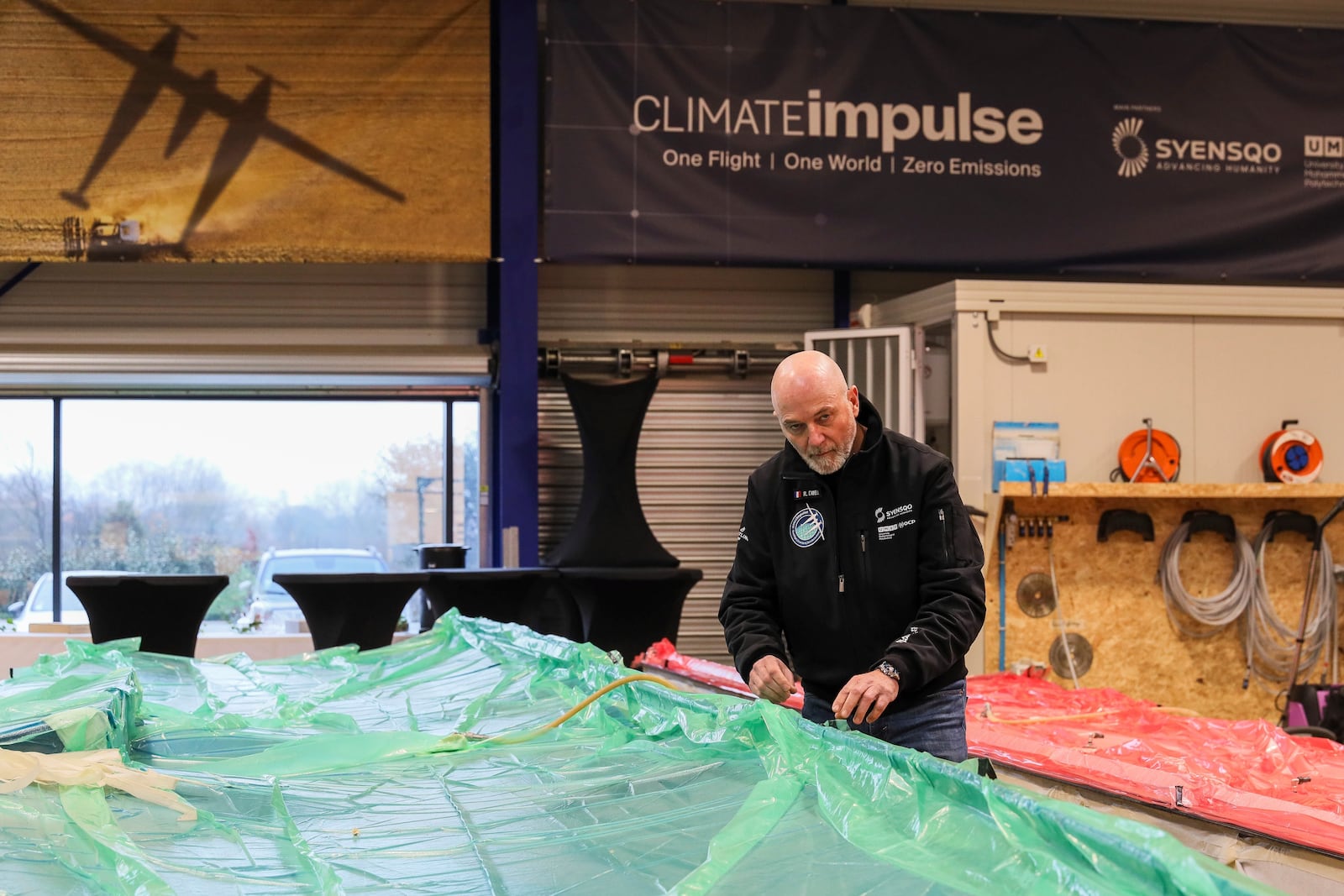 Raphael Dinelli, Climate Impulse engineer and co-pilot, stands near wings of the plane, powered by liquid hydrogen, at a press presentation of the project in a hangar in Les Sables d'Olonne, France on Thursday, Feb. 13, 2025.(AP Photo/Yohan Bonnet)