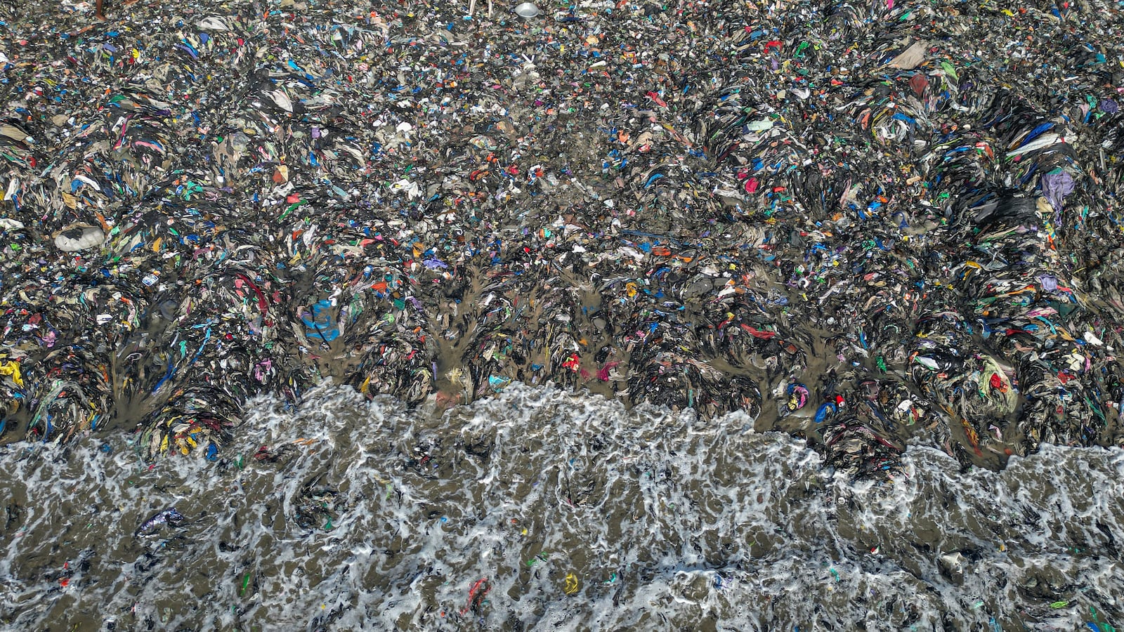 Textile waste pollutes the beach shore at Jamestown in Accra, Ghana, Saturday, Oct. 19, 2024. (AP Photo/Misper Apawu)