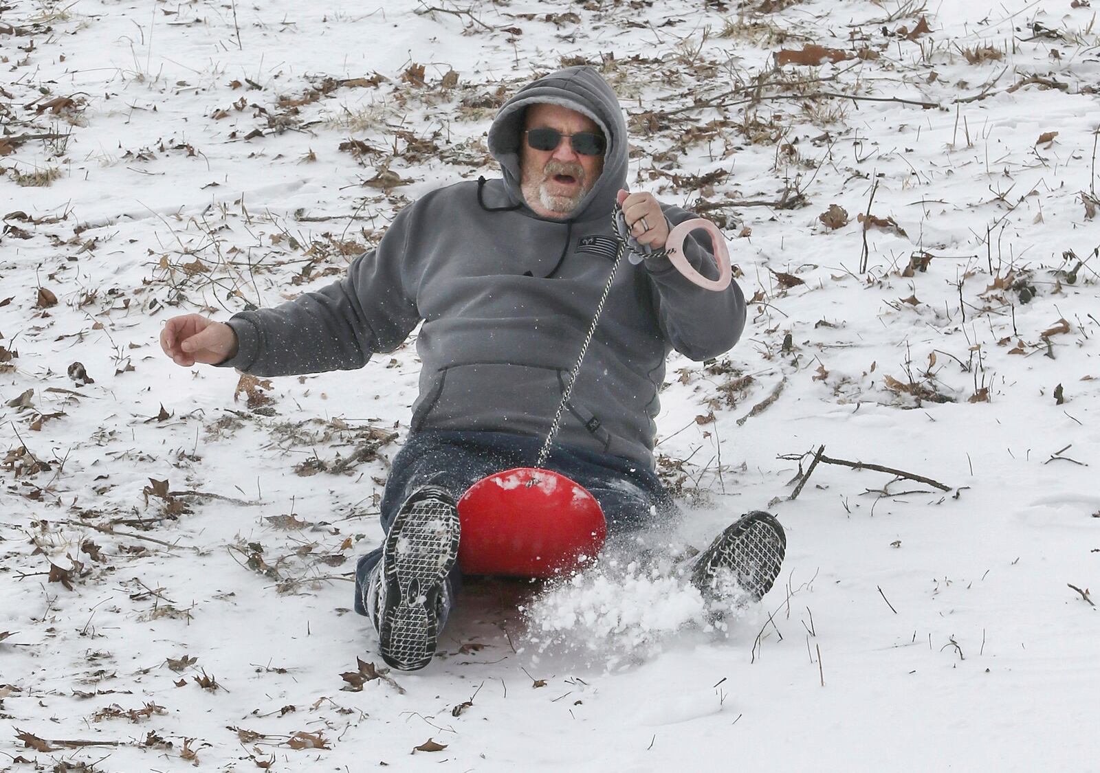 David Barnett holds on tight to his sled as he comes down the hill in the snow on Wednesday at Chautauqua Park in Owensboro, Ky., on Feb. 19, 2025. (Alan Warren/The Messenger-Inquirer via AP)