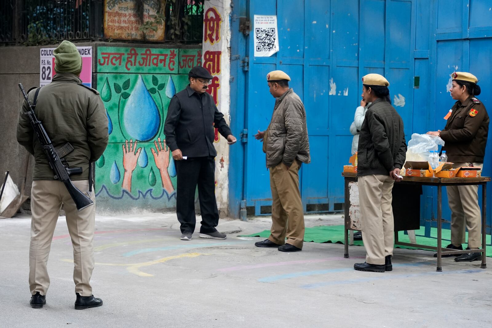 A police officer checks the identity card of a voter before they enter into a polling booth for the capital’s state legislature election in New Delhi, India, Wednesday, Feb. 5, 2025. (AP Photo/Piyush Nagpal)