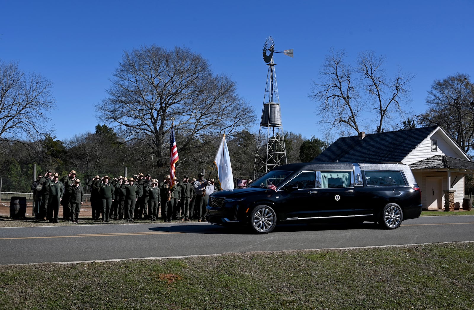 NPS employees, based out of Sumter County, Ga., salute the hearse carrying the flag-draped casket of former President Jimmy Carter as the motorcade stops in front of the Boyhood Farm, where President Carter grew up, Saturday, Jan. 4, 2025, in Plains, Ga. (Hyosub Shin/Atlanta Journal-Constitution via AP, Pool)