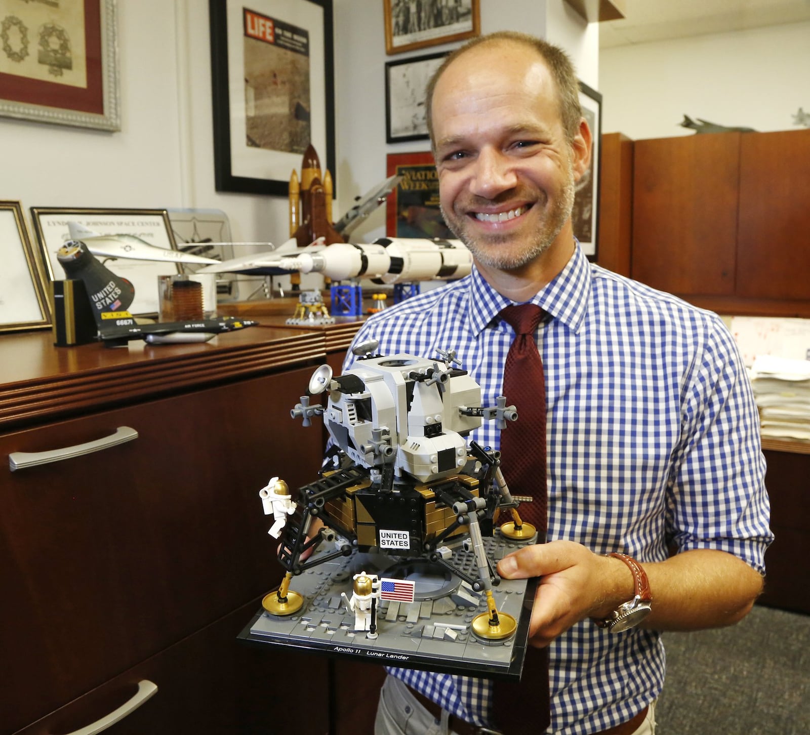 Air Force Research Laboratory Senior Historian Kevin Rusnak with a lunar lander model and other Apollo memorabilia in his office at Wright-Patterson Air Force Base. AFRL projects helped advance rocket engines, space suits and parachute technology for the Apollo program. TY GREENLEES / STAFF