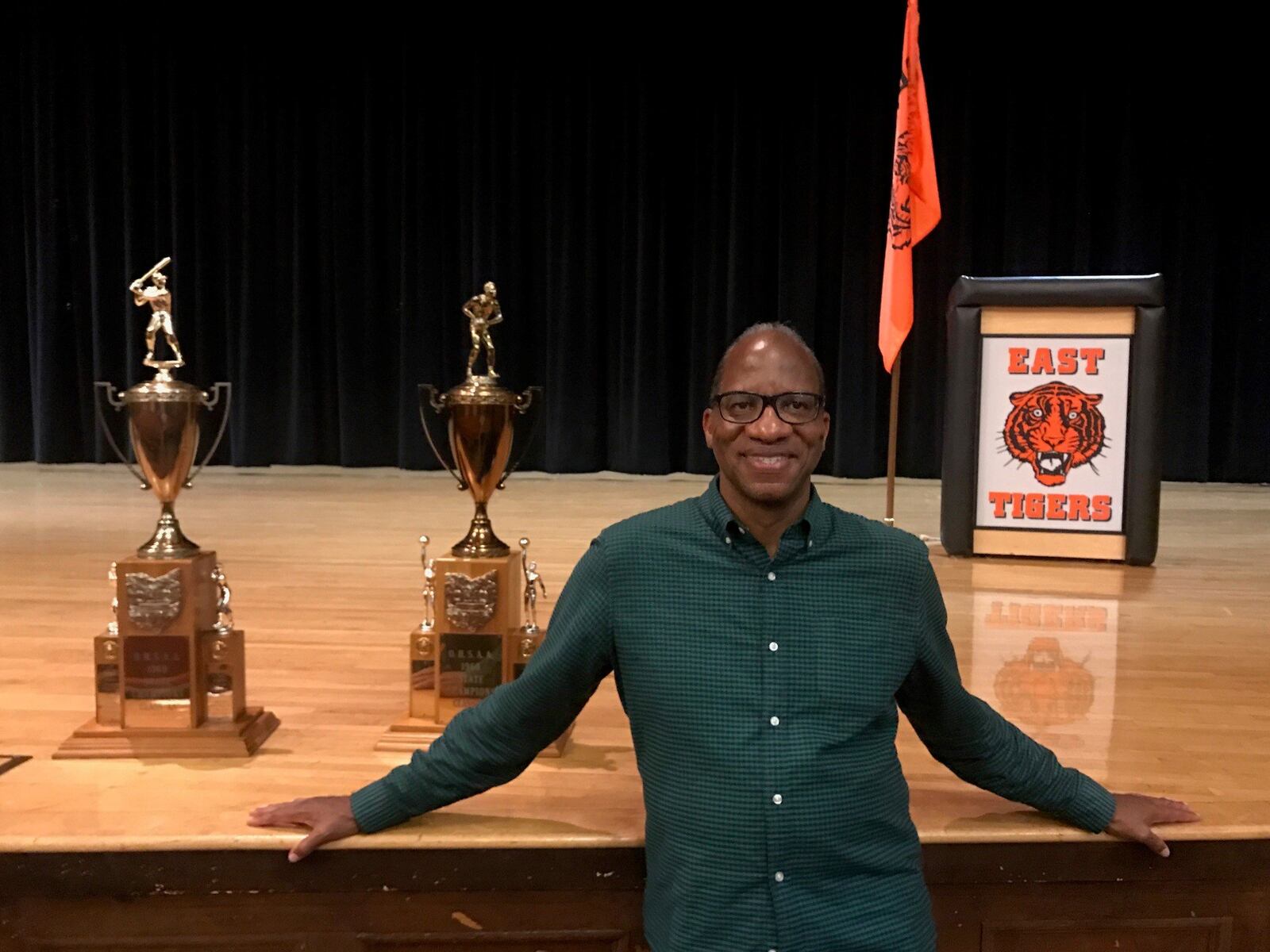 New York times best-selling author author, award-winning journalist and Miami University former basketball player, grad and distinguished visiting professor Wil Haygood at East High with championship trophies from 1968-69. Haygood will appear three times in Dayton over the next month (as part of UD Speaker Series on Tuesday, as part of Dayton Literary Peace Prize Community Conversations on Oct. 11 at the Dayton Metro Library and at Books a Million in The Greene Oct. 26. Tom Archdeacon/STAFF